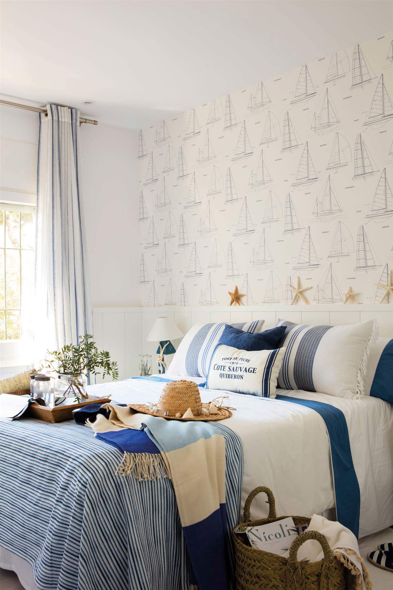 Dormitorio con ropa de cama azul y papel pintado de barquitos