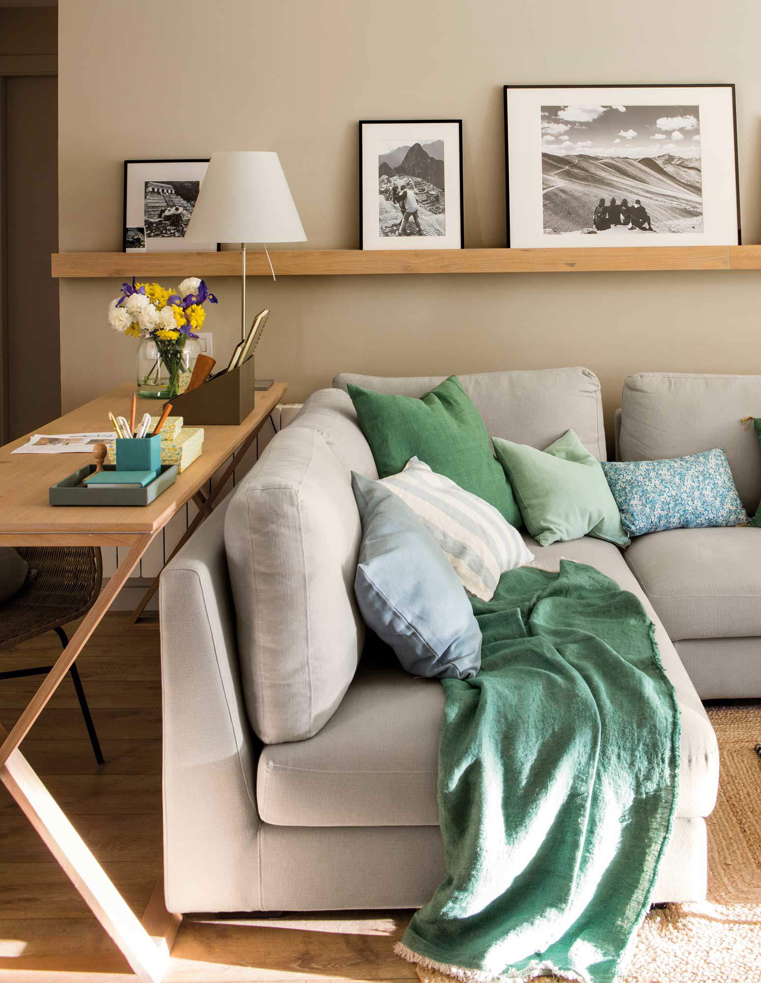 Salón con sofá en gris claro y cojines verdes.