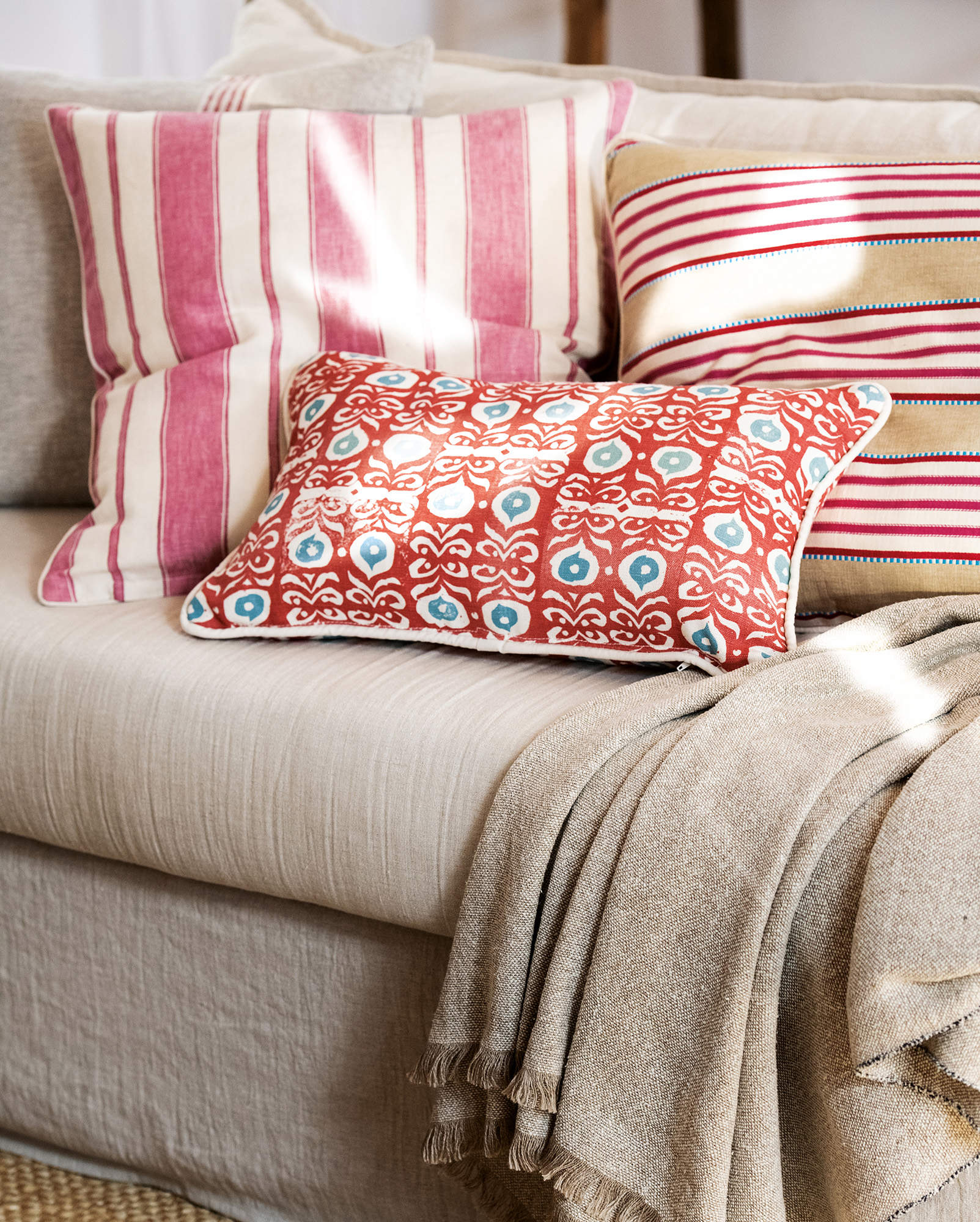 Detalle de los cojines en tonos rojo, rosa y fresa en el sofá. 