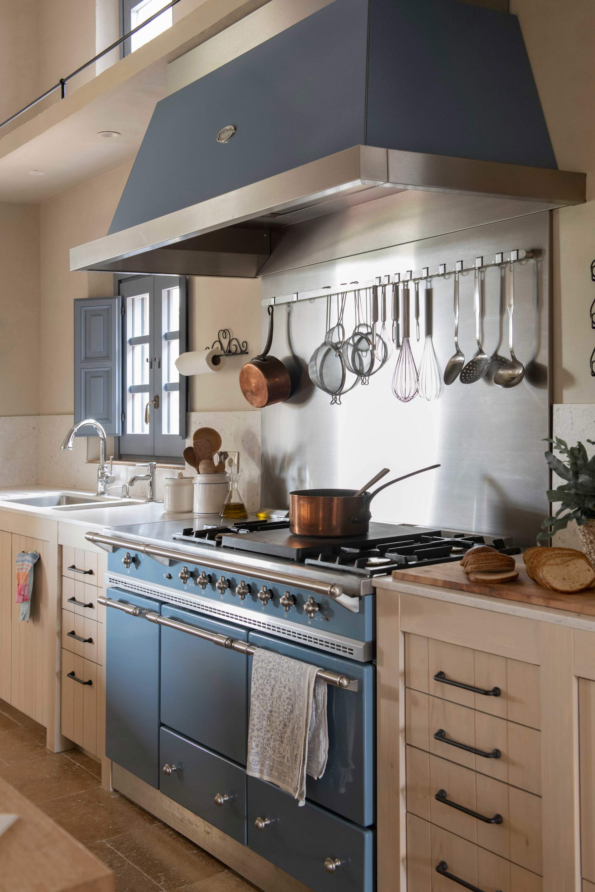 Cocina rústica con utensilios de cobre y típica cocina francesa industrial en azul