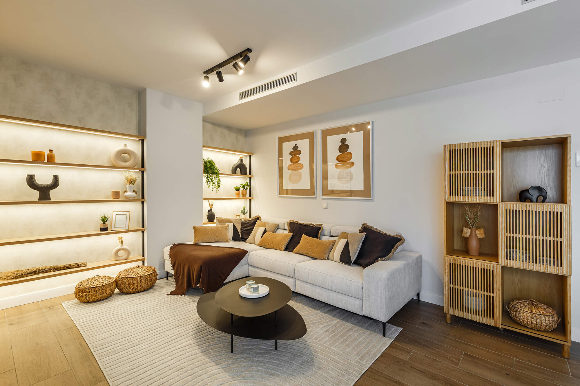 Salón con sofá gris, mesas nido, estantería de madera y estantería a medida