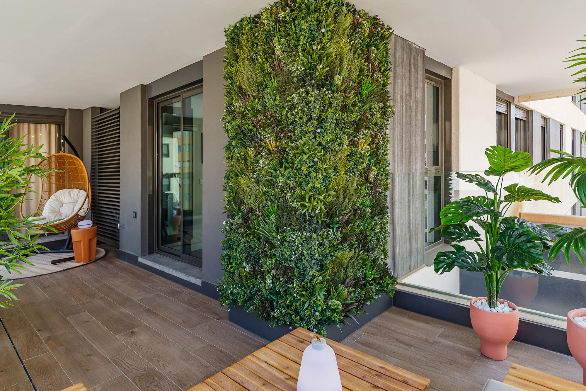 Terraza decorada con plantas, un jardín vertical y un columpio de fibras