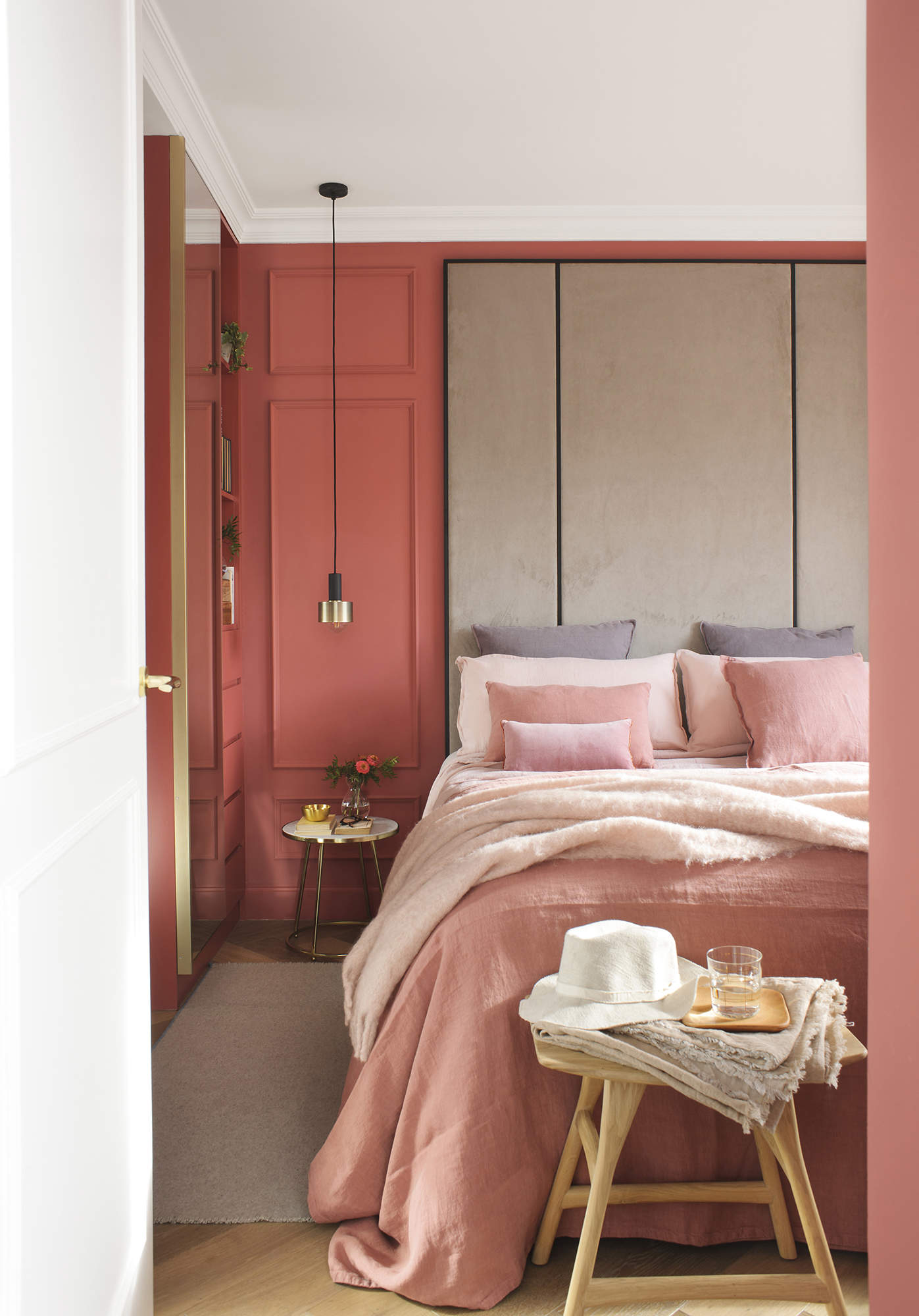 Dormitorio con gran cabecero a medida y paredes con molduras de color rosa