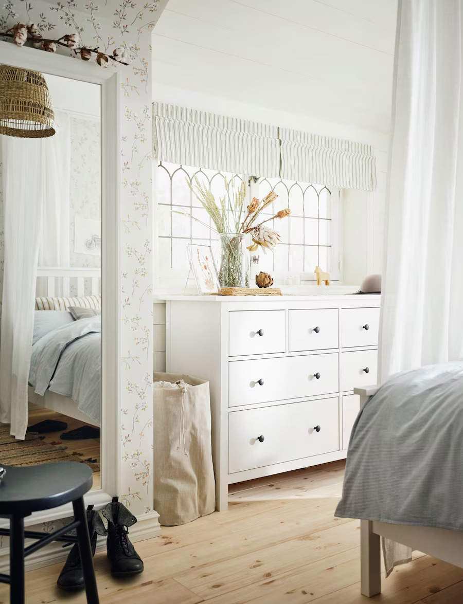 Dormitorio empapelado con muebles blancos y decoración sencilla