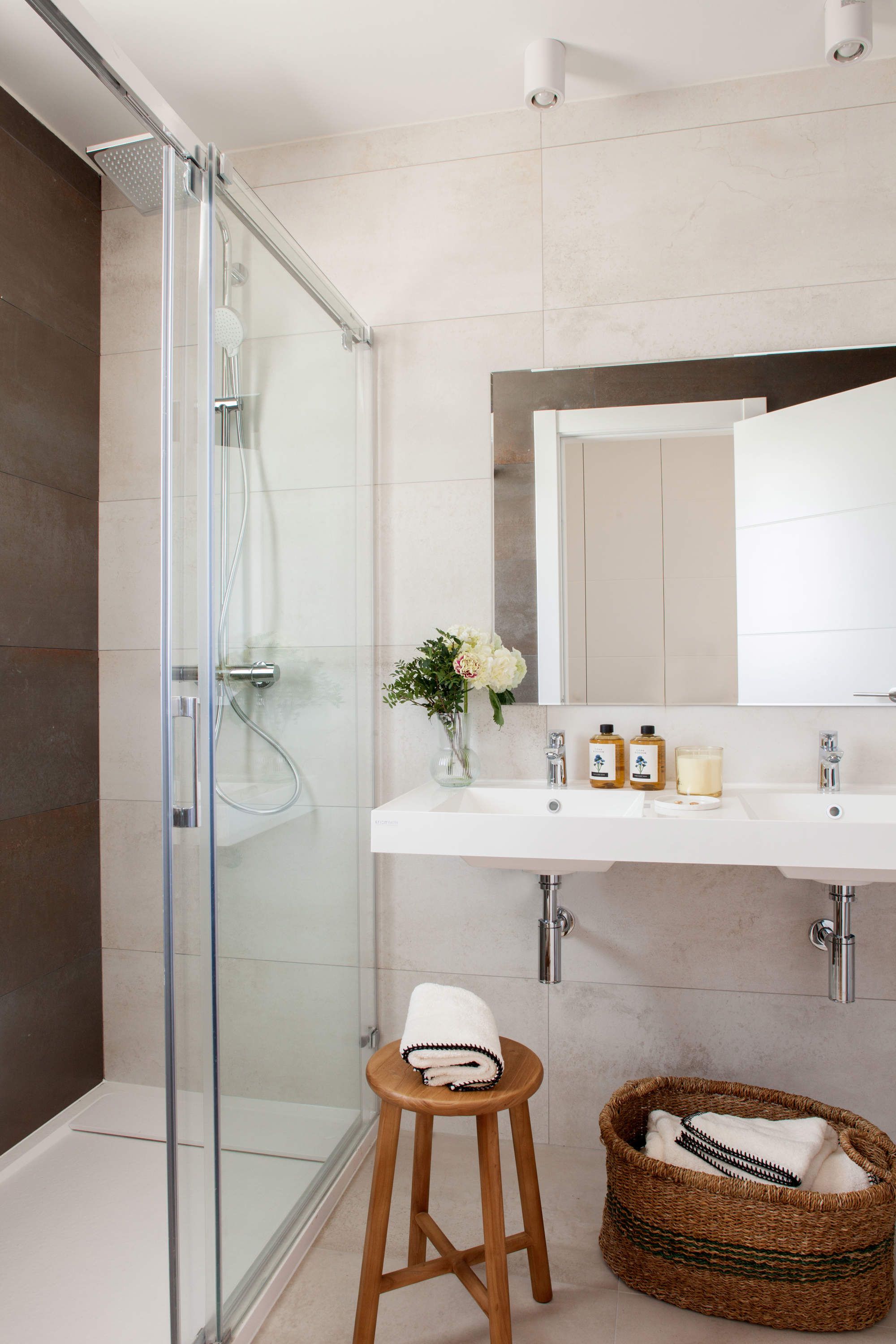 Baño del dormitorio en suite con ducha y mampara con azulejos de mármol.