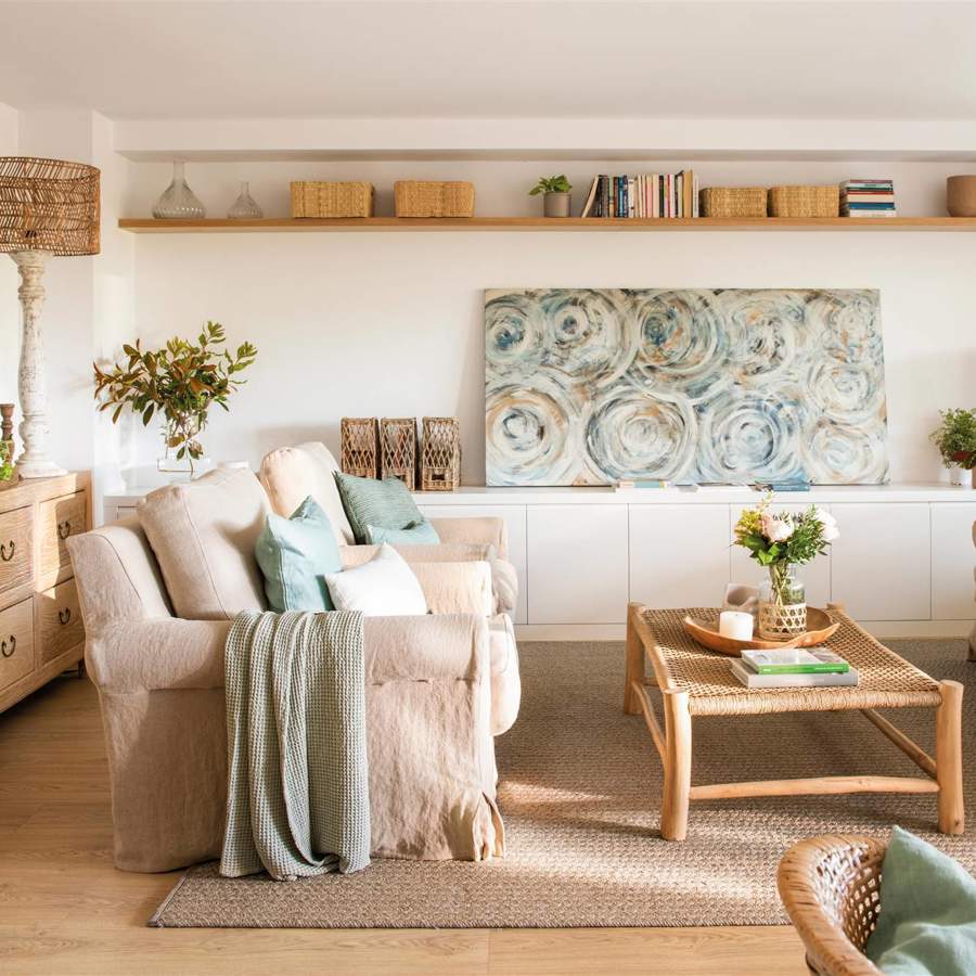 Salón en colores neutros con balda de madera, aparador bajo blanco, sofá de lino y cuadro verde abstracto