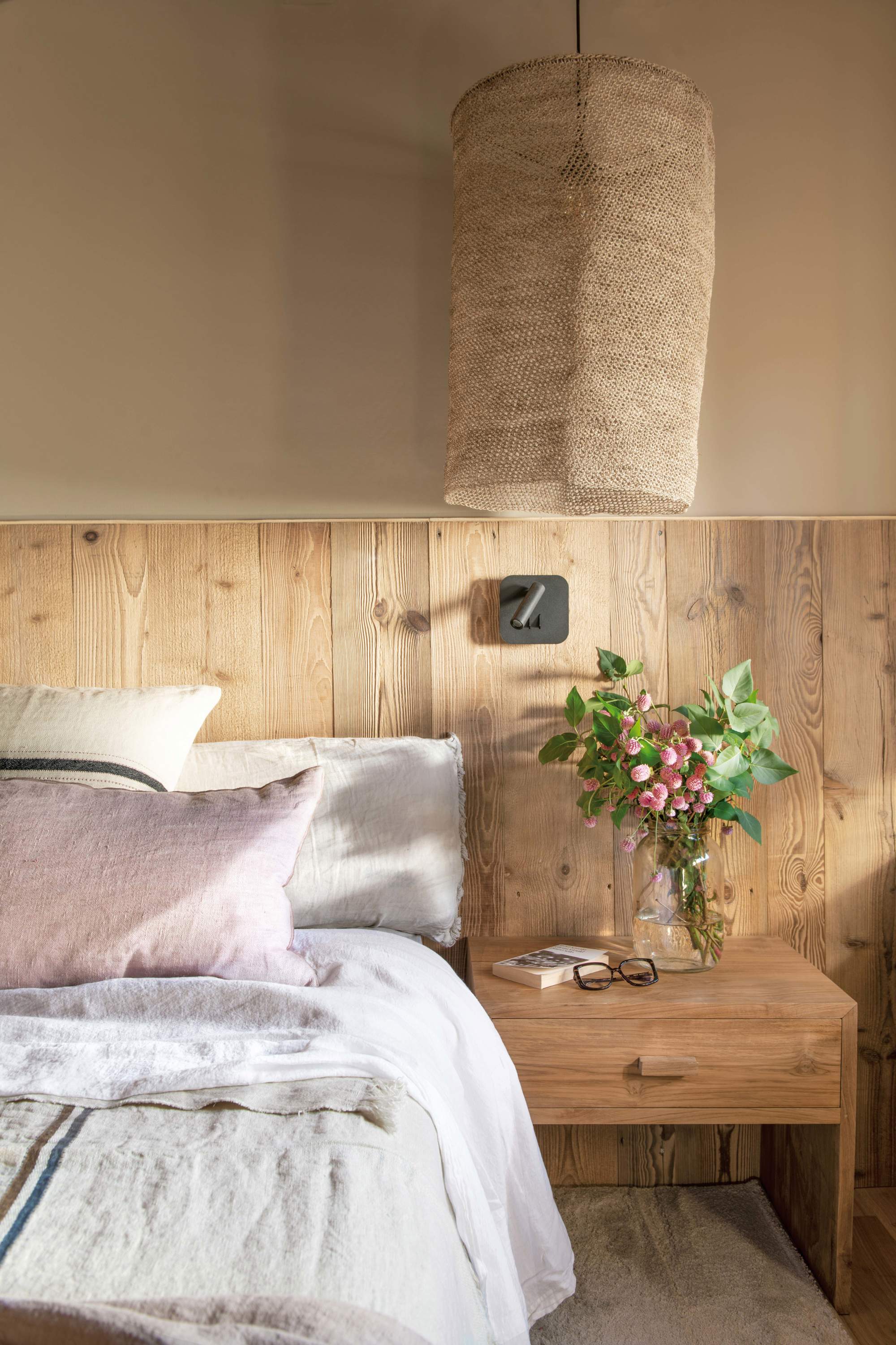 Dormitorio con mesilla de madera, pared con arrimadero y lámpara suspendida