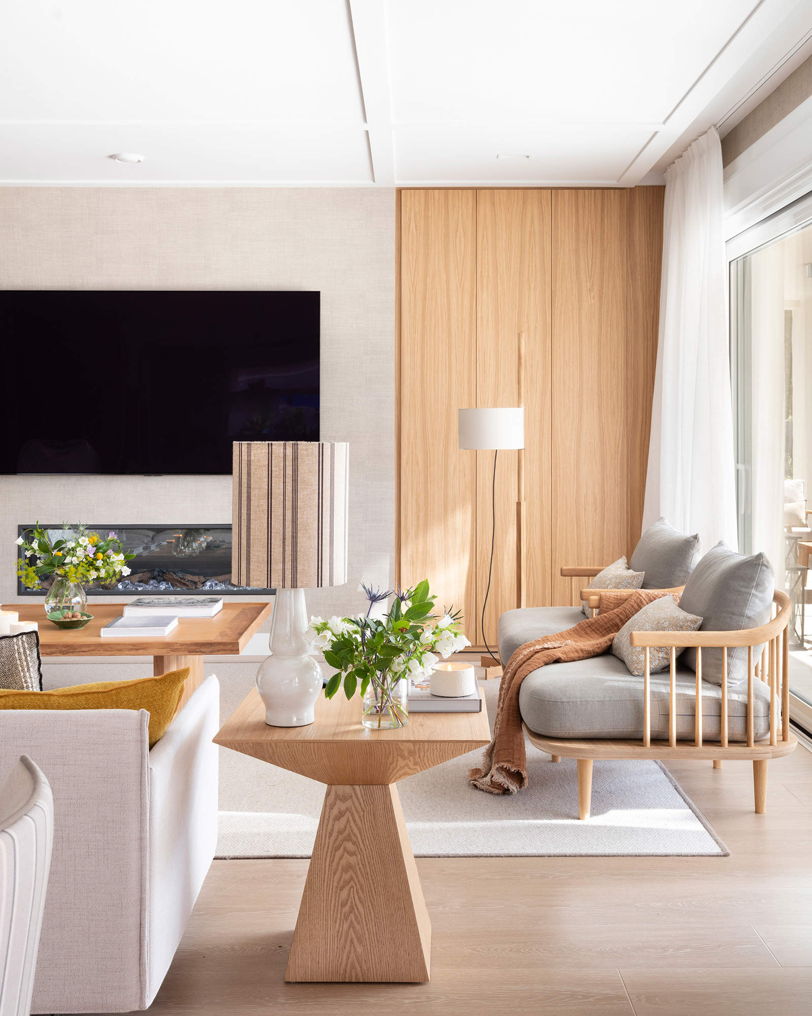 Salón moderno con muebles de madera y televisor en la pared de la chimenea