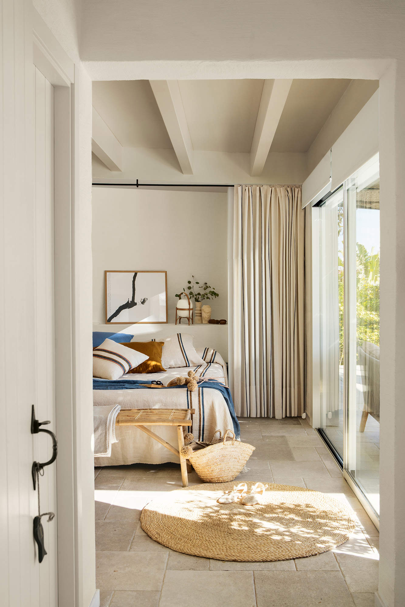 Dormitorio mini con armarios de obra a cada lado de la cama y cortina de tela como puerta 