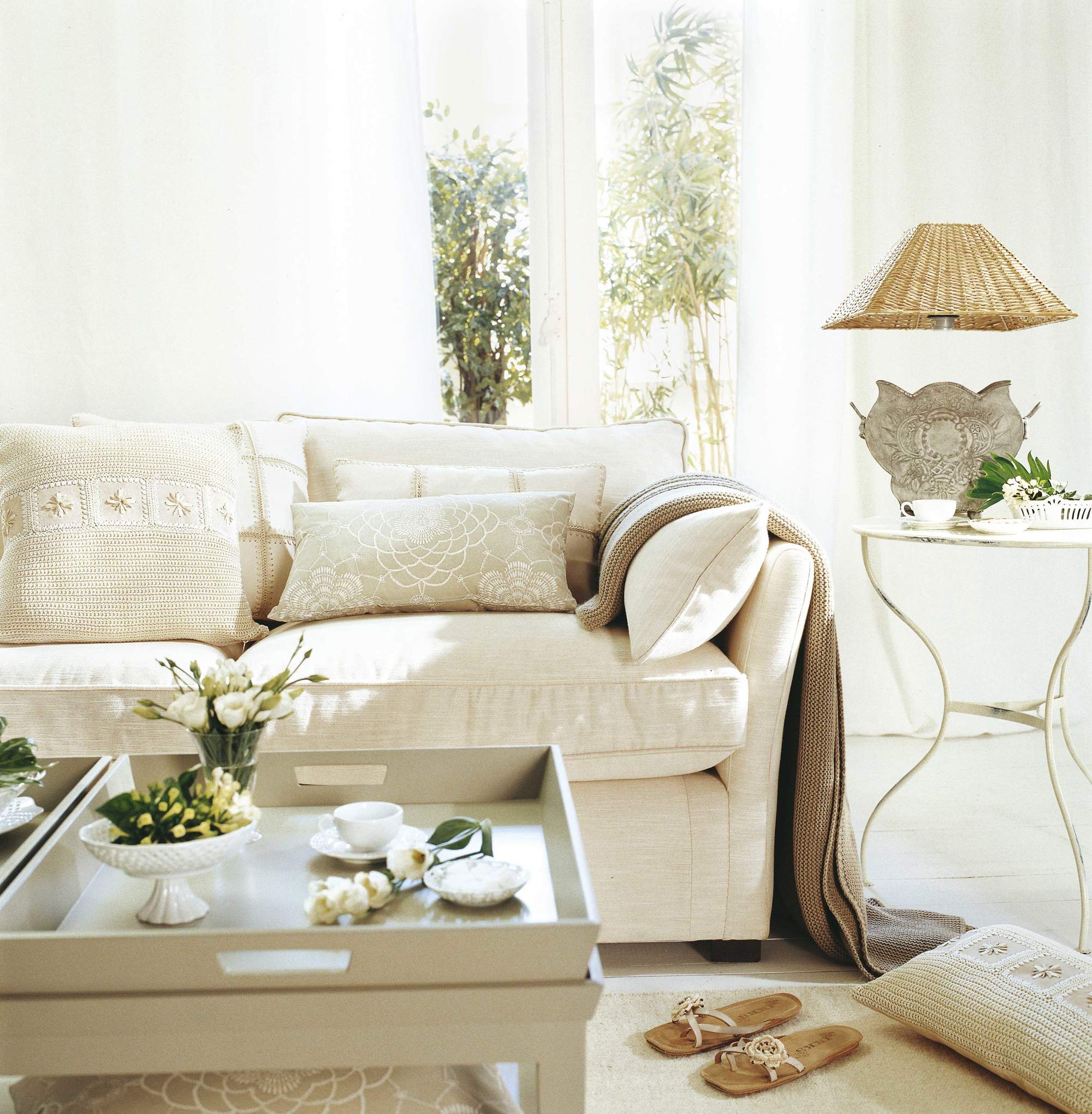 Salón con sofá blanco, mesa auxiliar de jardín y lámpara con pie de maceta