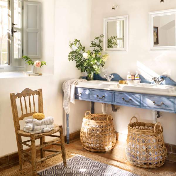 Baño con mueble de lavabo con cajones lacado en añil, espejos, cestas, silla y toallas