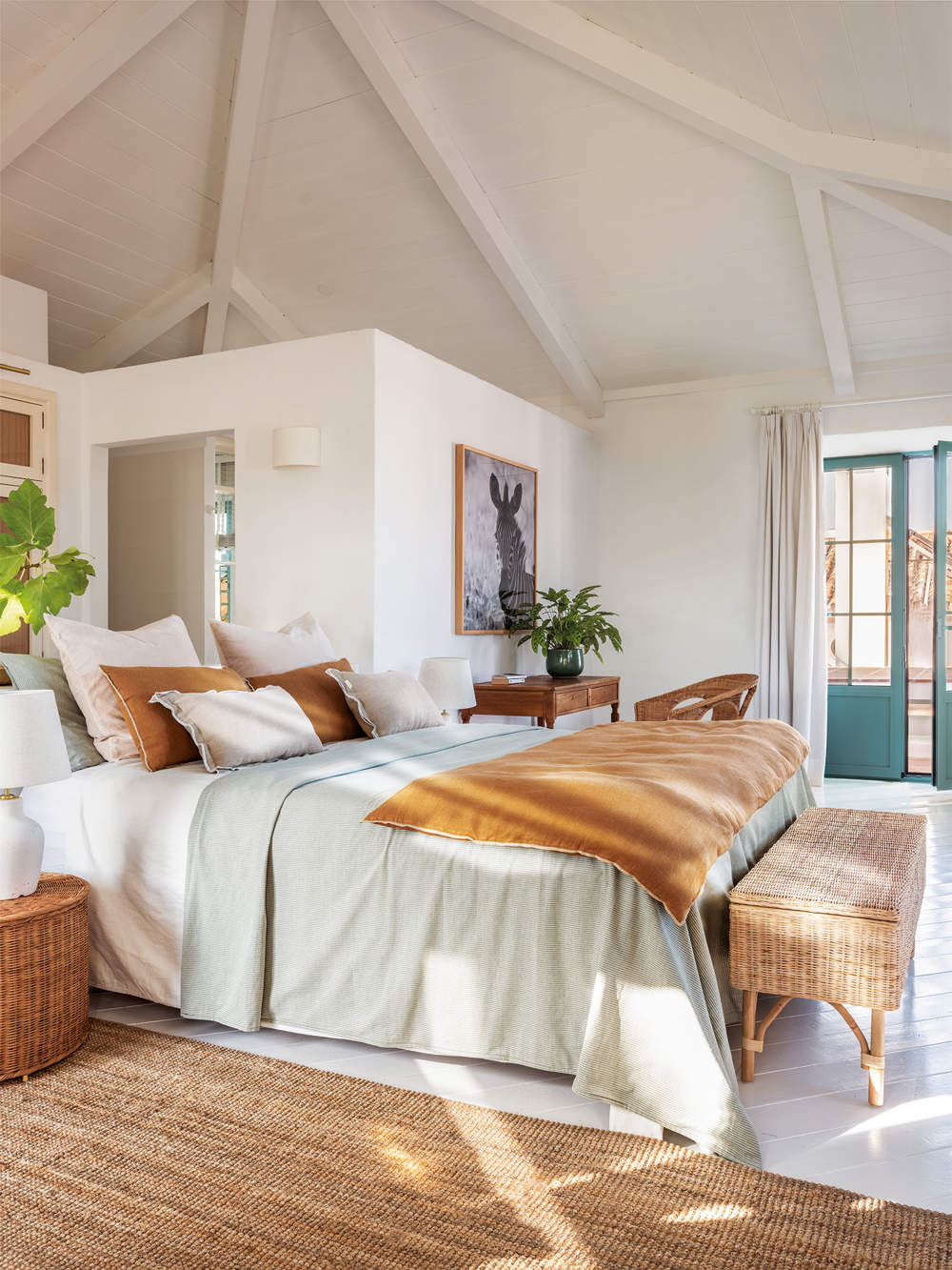 Dormitorio rústico moderno blanco con ropa de cama color tierra y alfombra de yute