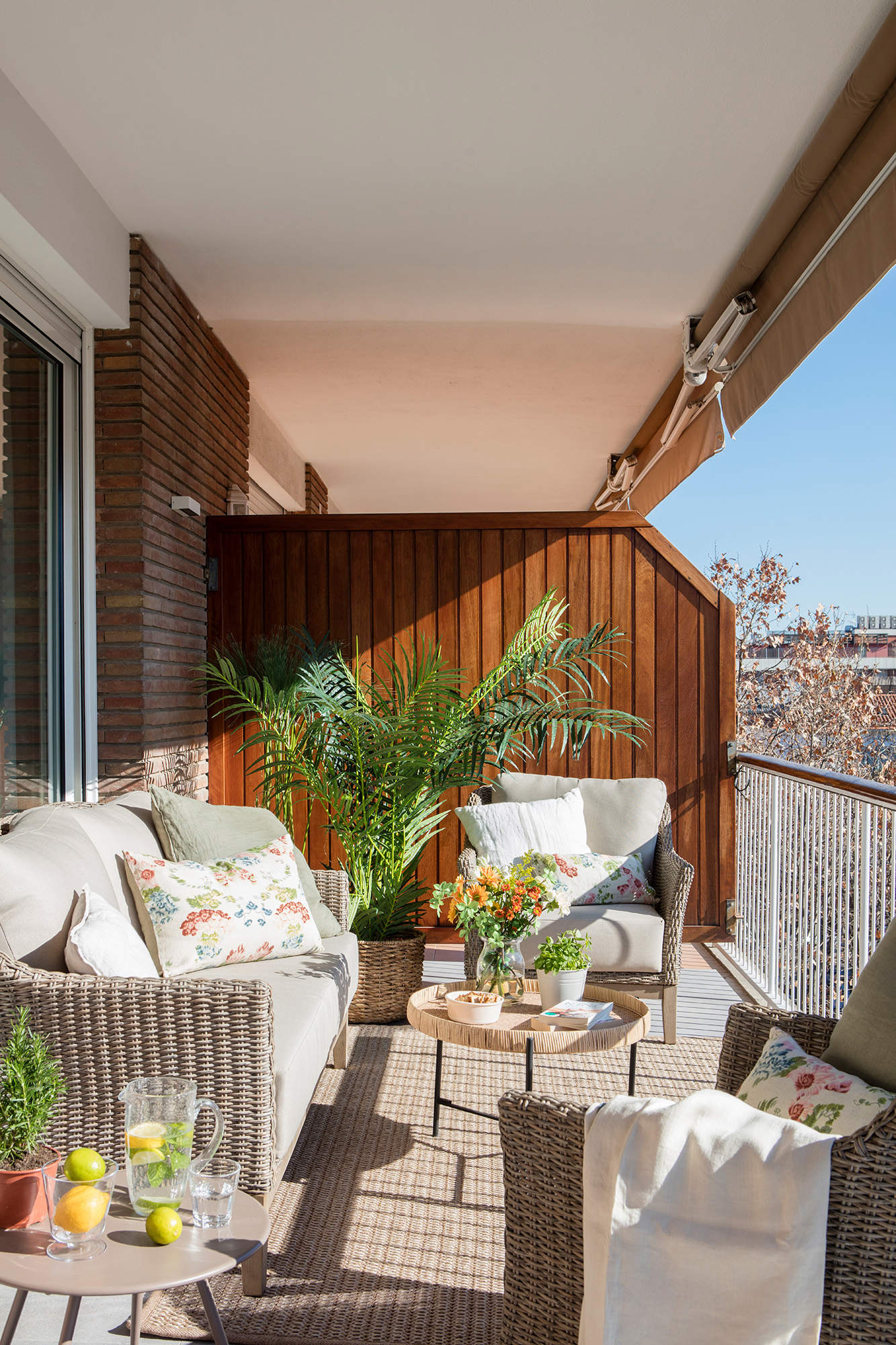 Terraza pequeña decorada con un sofá y dos butacas alrededor de una mesa de centro.