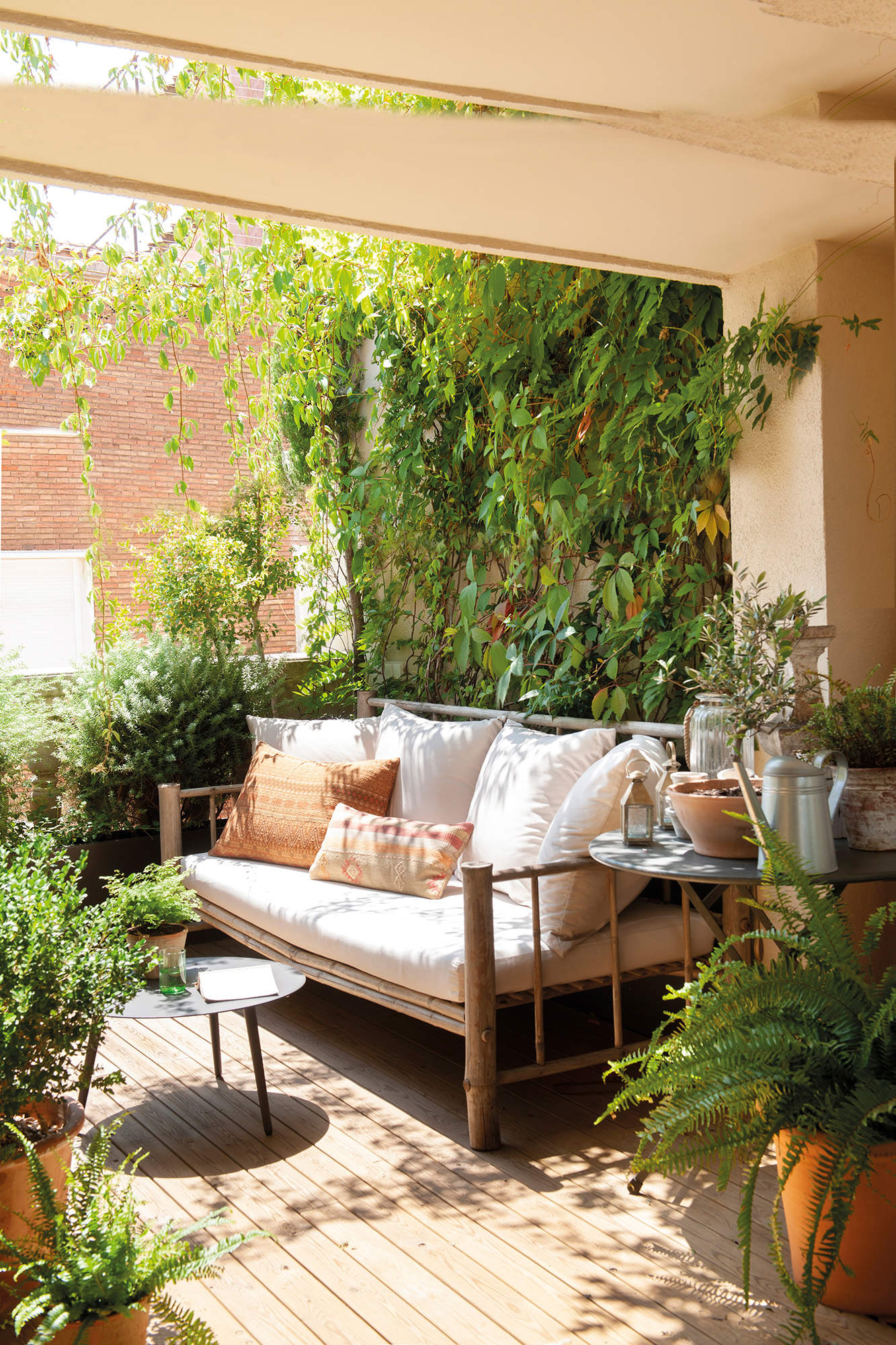 Terraza pequeña con un sofá y mucha vegetación.