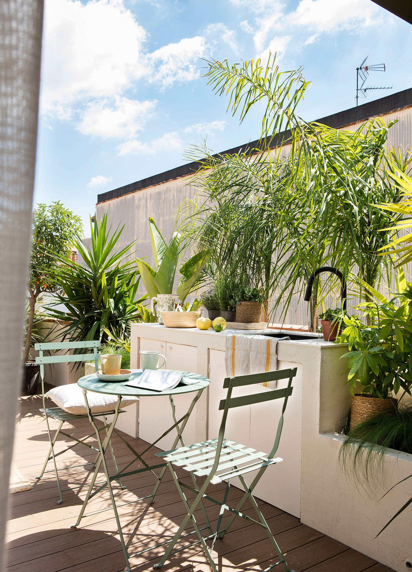 Terraza pequeña decorada con un velador de forja y dos sillas plegables.