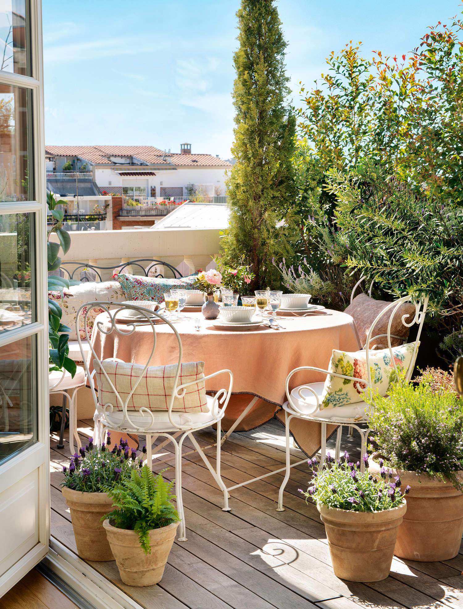 Una terraza con muebles de forja y tonos empolvados