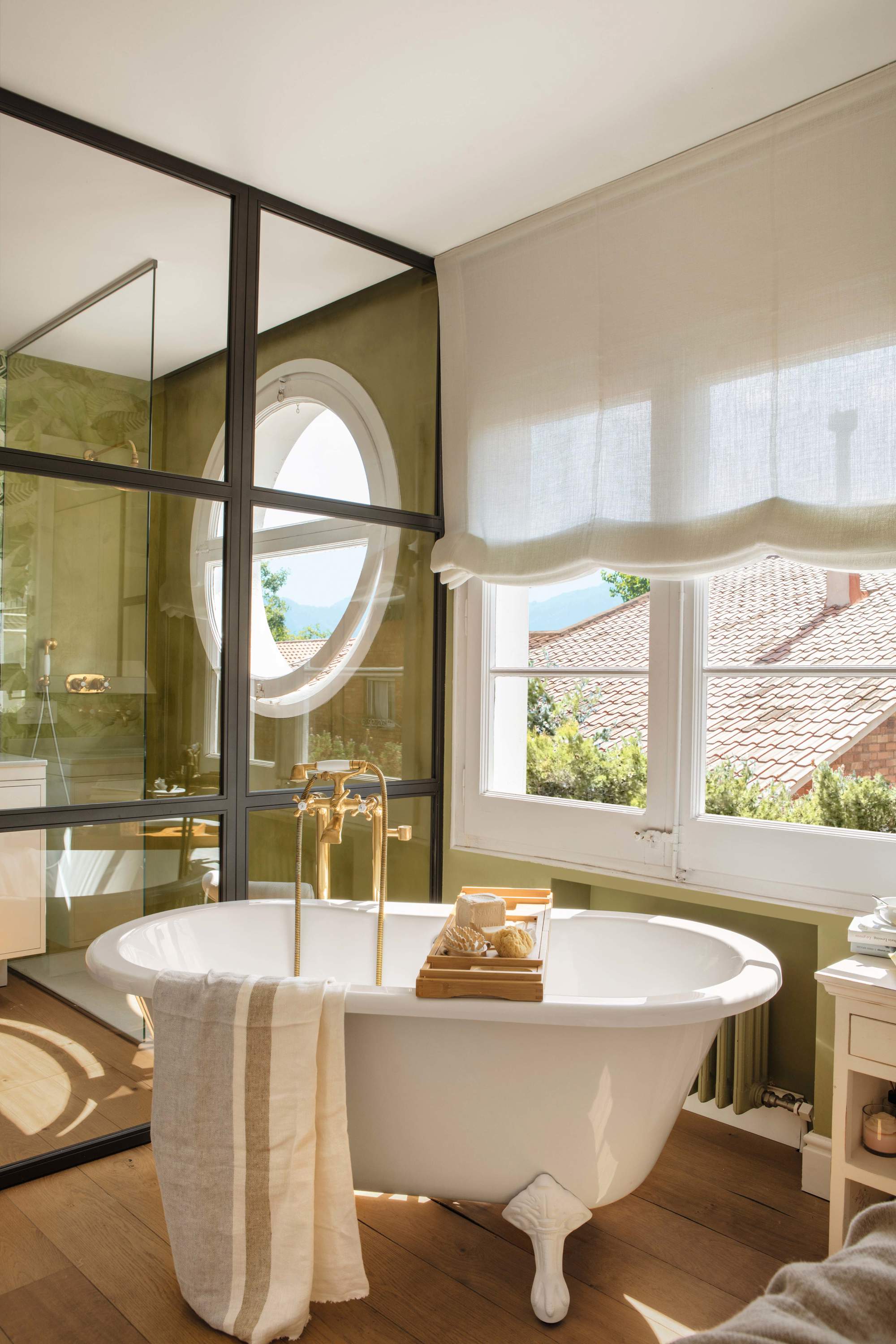 Bañera exenta con grifería vintage dorada en baño verde