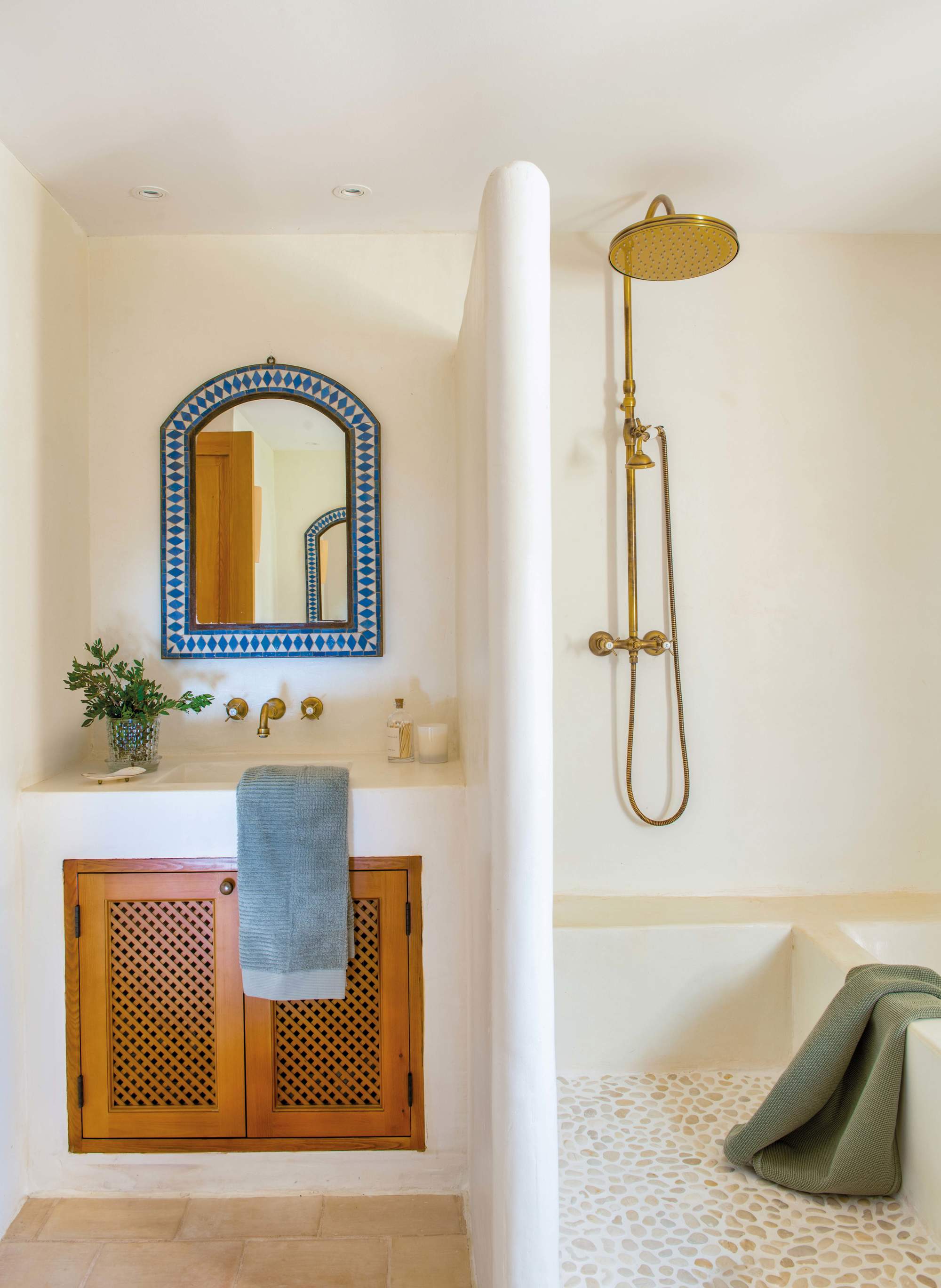 Baño con lavabo, espejo de mosaico y ducha con grifería dorada