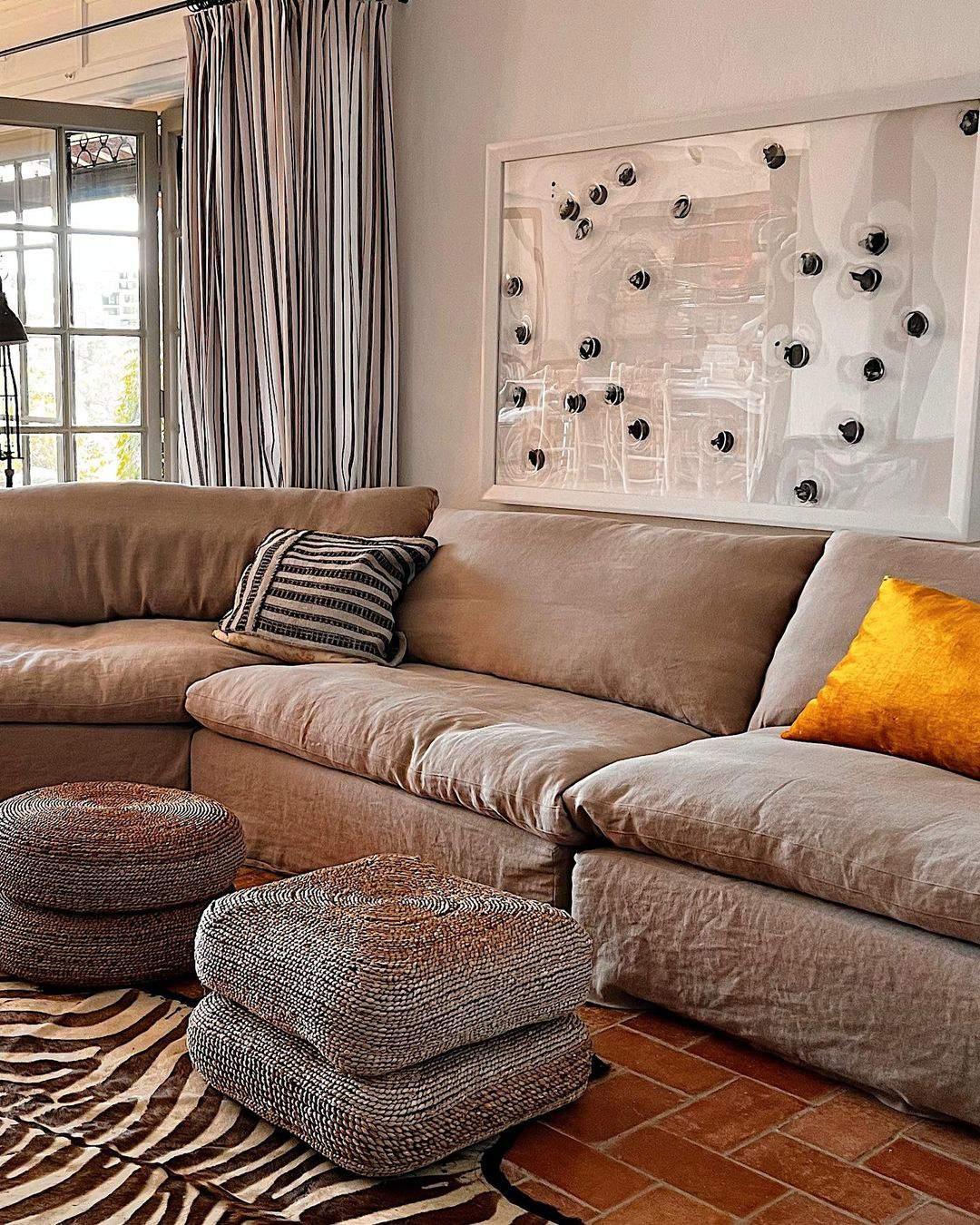Salón con sofá modular, pufs de fibras y cuadro moderno