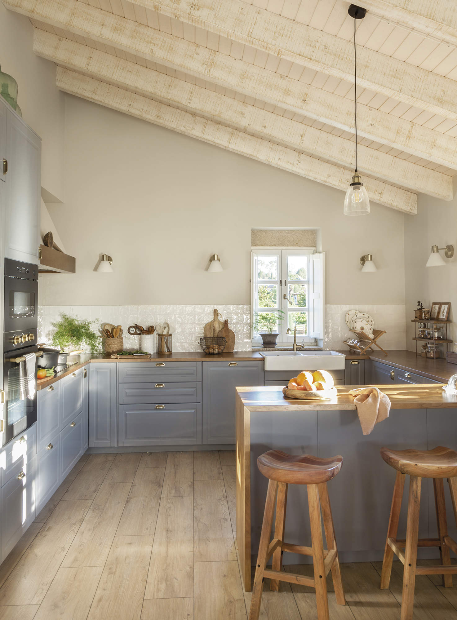 Cocina azul con techo con vigas de estilo rústico