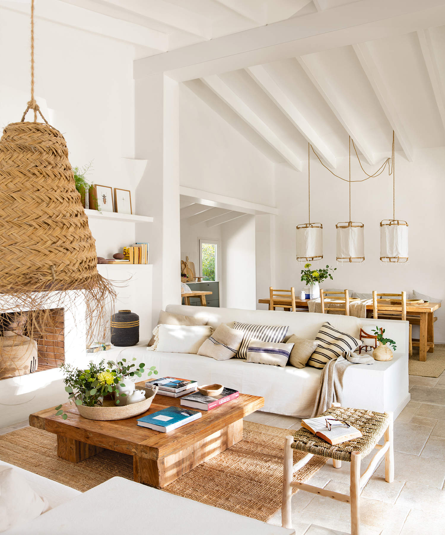 Salón de verano blanco con muebles de madera y detalles en fibra natural.