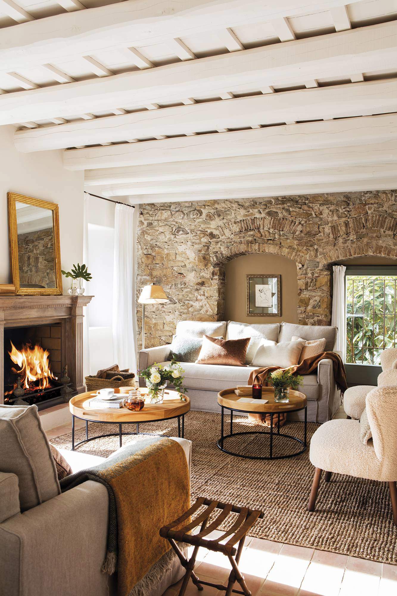 Salón rústico con pared de piedra y vigas de madera