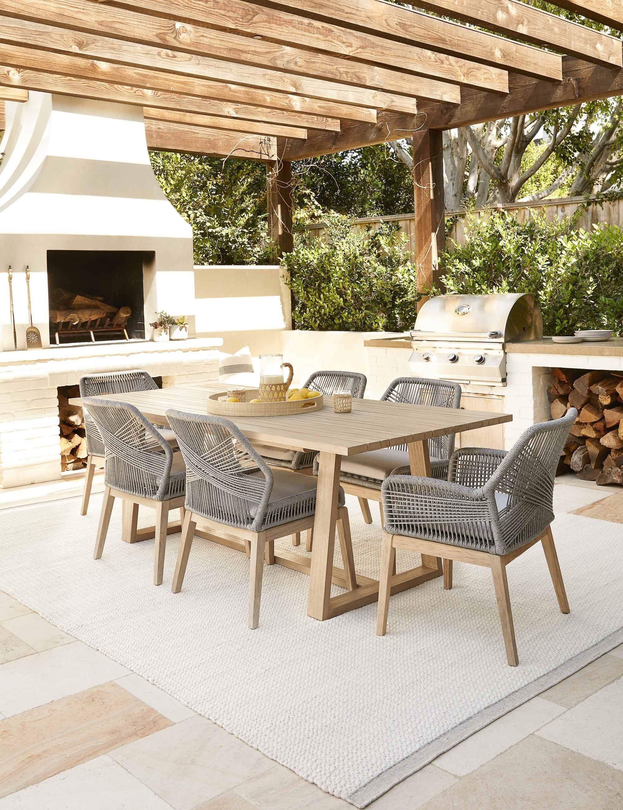 Cocina exterior con mesa de comedor de madera y sillas de fibras en color gris