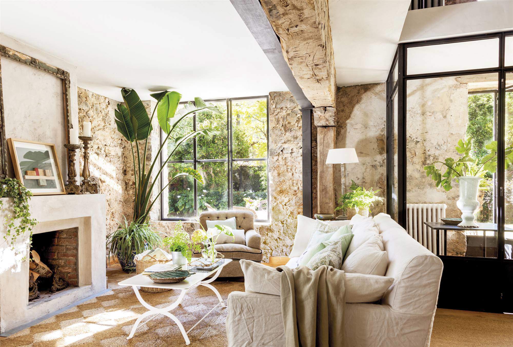 Salón con chimenea, paredes de piedra y muchas plantas