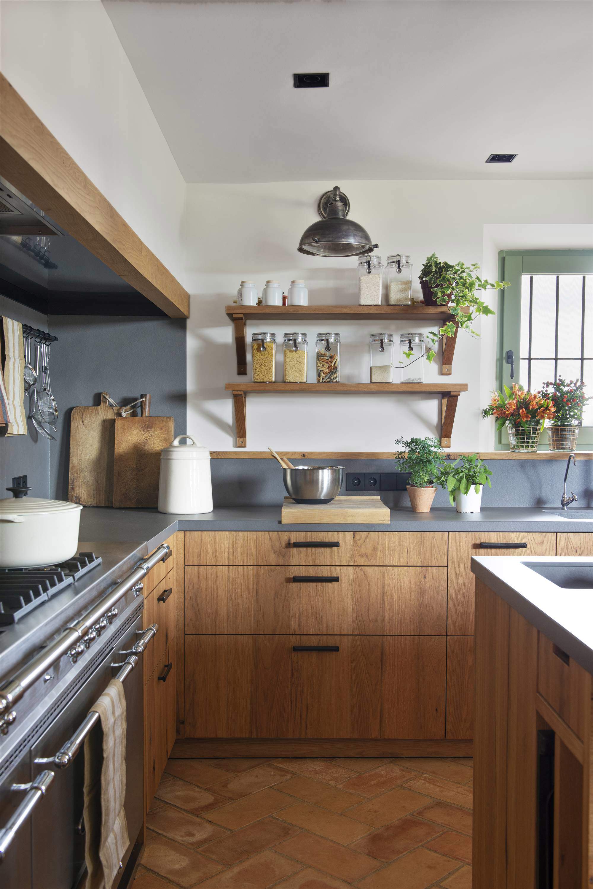 Cocina con muebles de madera, encimera gris y estantes de pared con escuadras