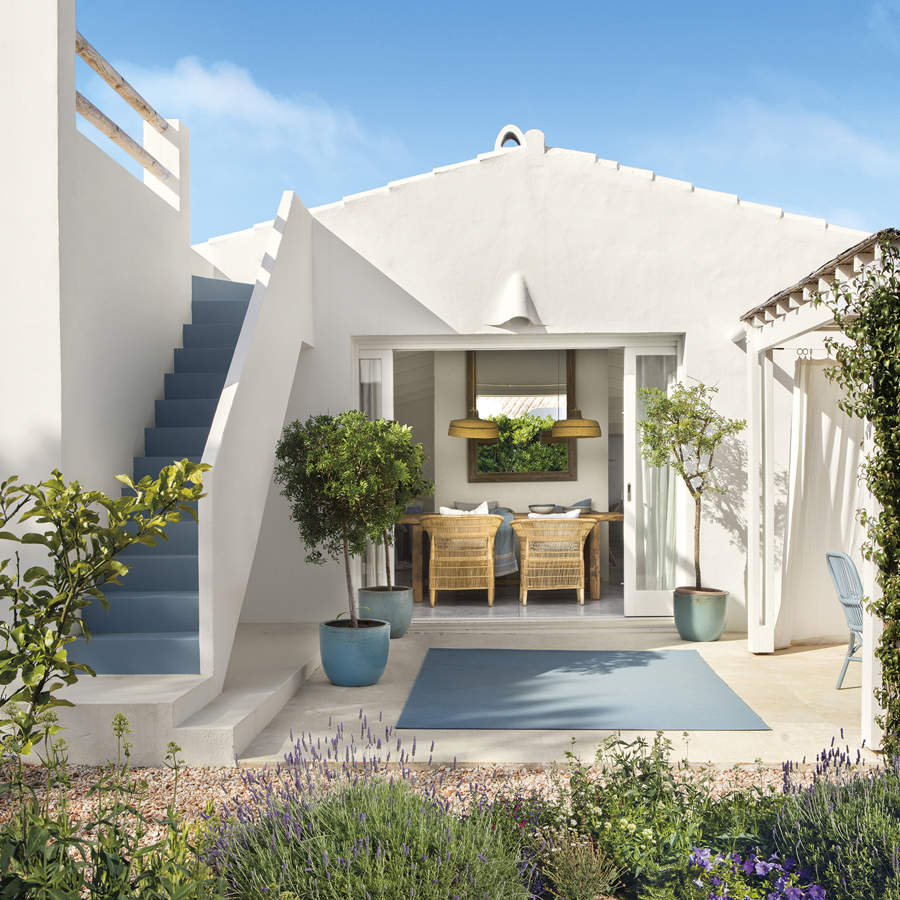 Porche estilo mediterráneo blanco y luminoso con alfombra azul