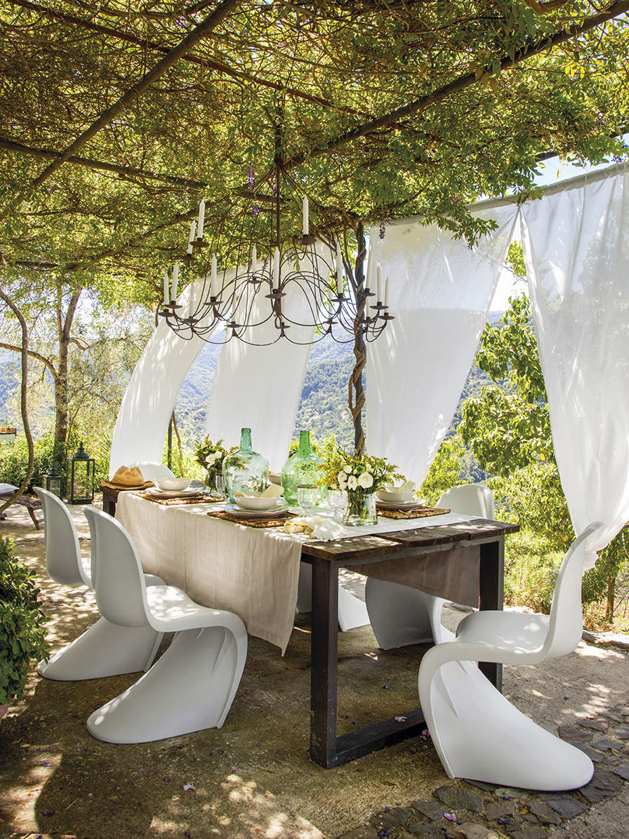 Comedor bajo porche de cañizo y trepadoras.