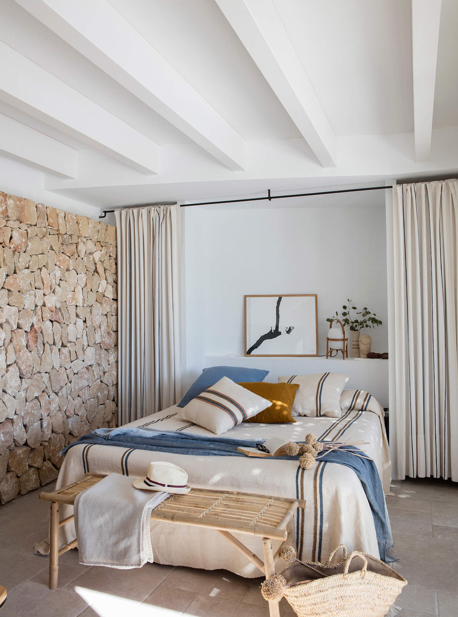 Dormitorio de verano con cama abatible, pared de piedra, cortinas que esconden armarios y ropa de cama azul