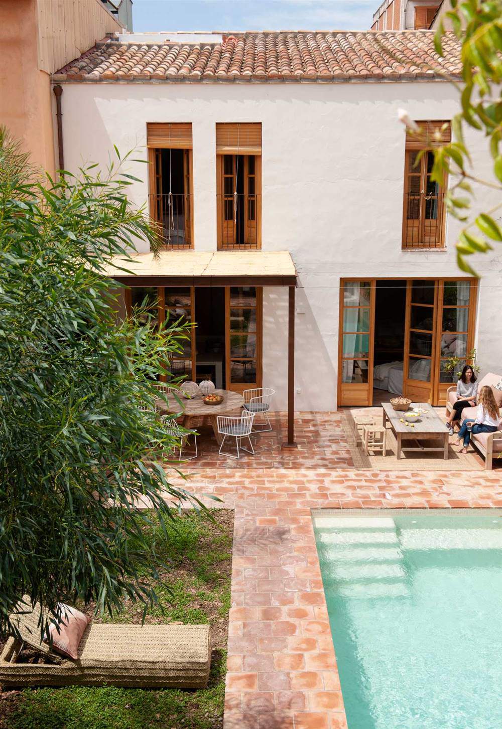 Un patio con zona de jardín y piscina de grandes dimensiones.