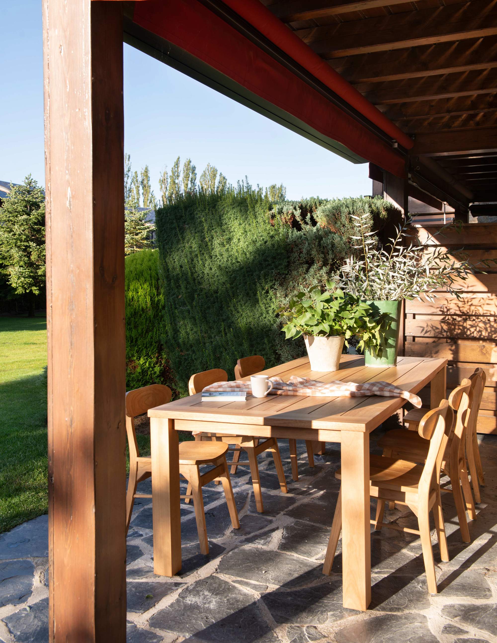 Comedor exterior de madera natural bajo pérgola 