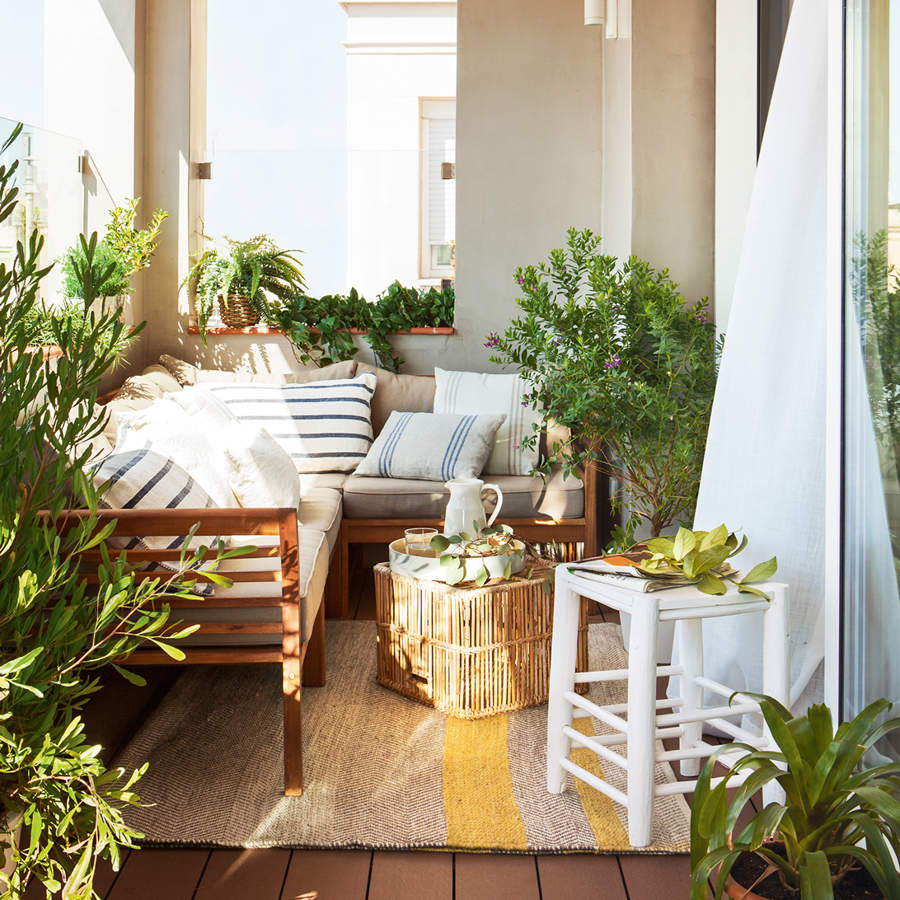 terraza pequena cubierta con sofa rinconero mesa de centro de cana taburete de madera y cojines vintage a rayas