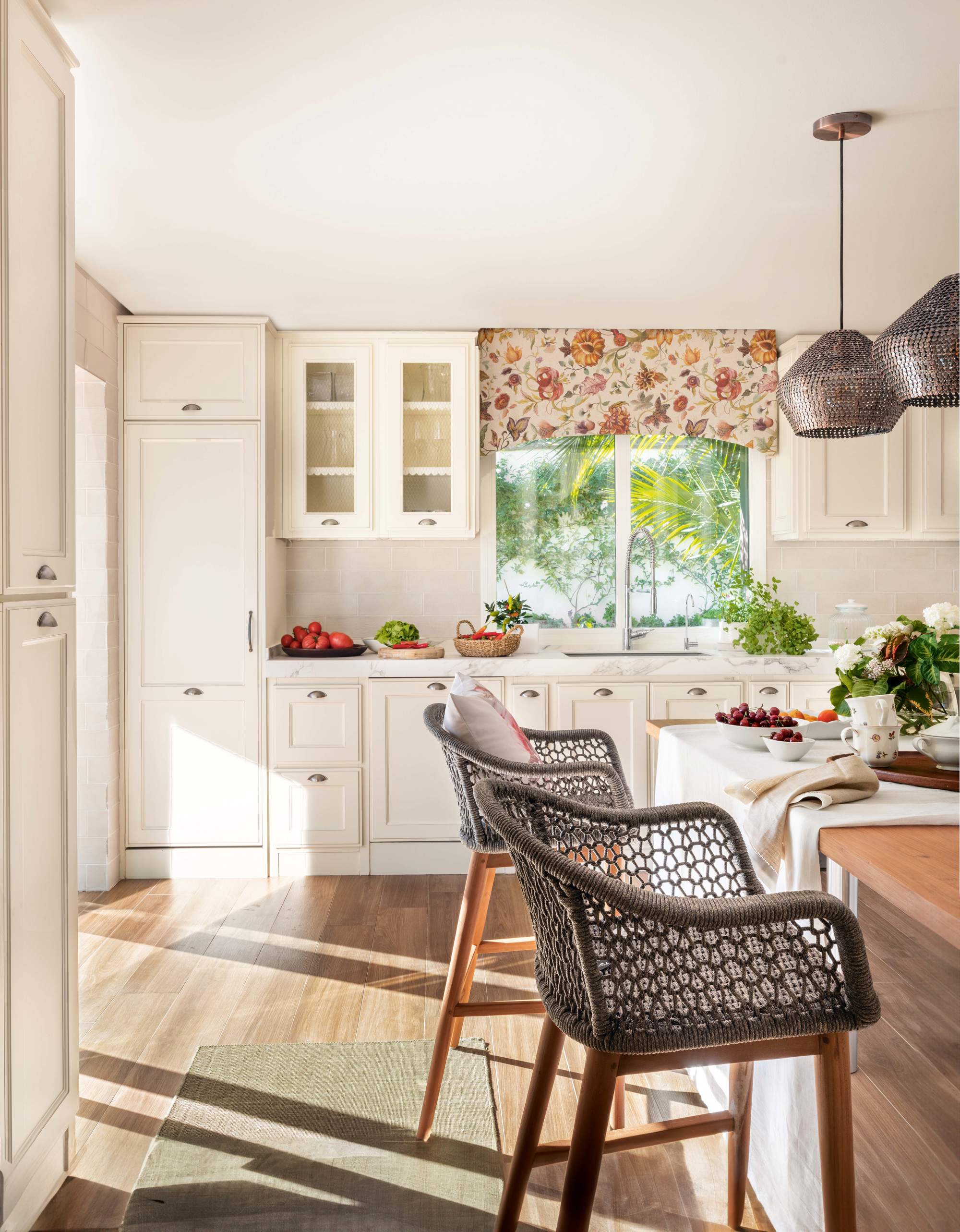 Cocina rústica blanca con muebles hasta el techo, módulo acristalado y cortinas de flores