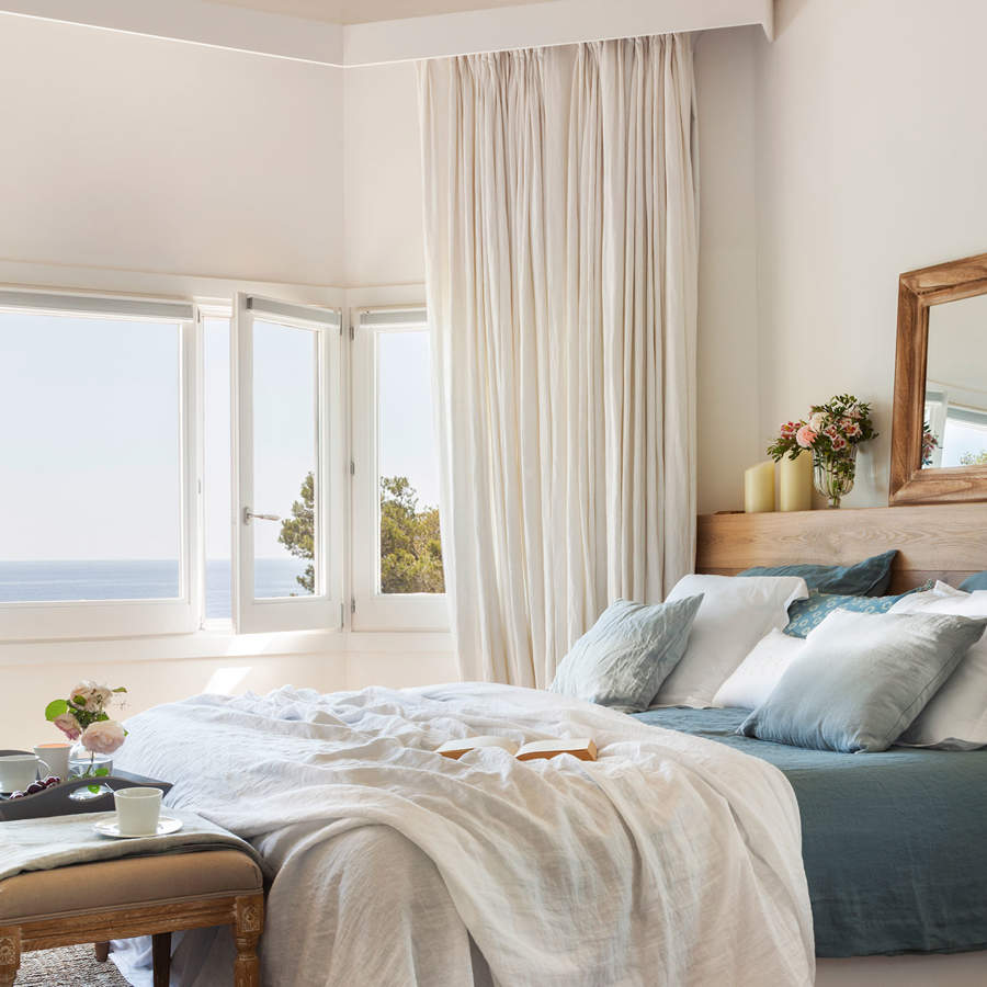 dormitorio con vistas al mar y ropa de cama en blanco y azul 172579e0