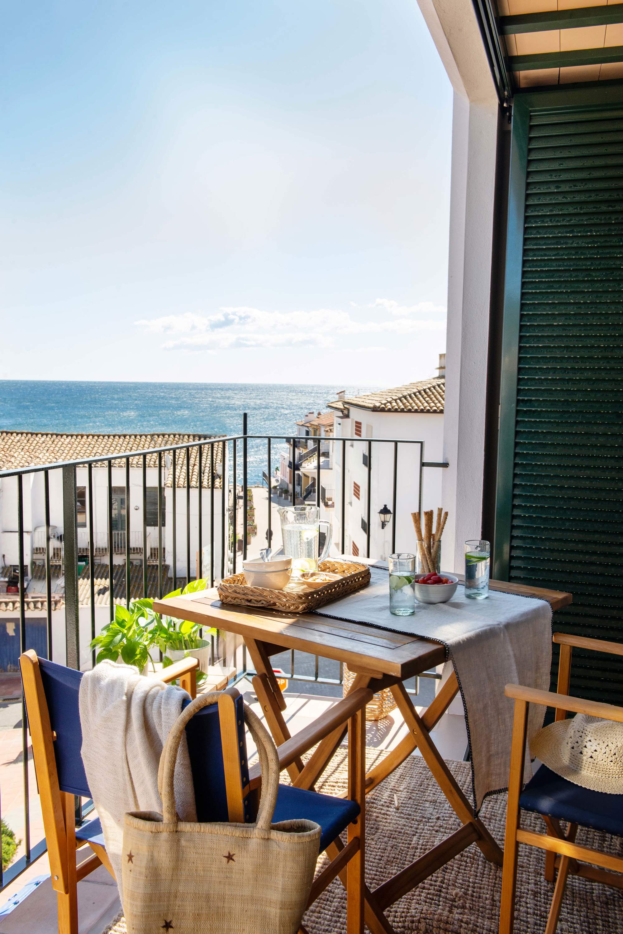 Terraza pequeña con barandilla metálica y muebles de madera plegables