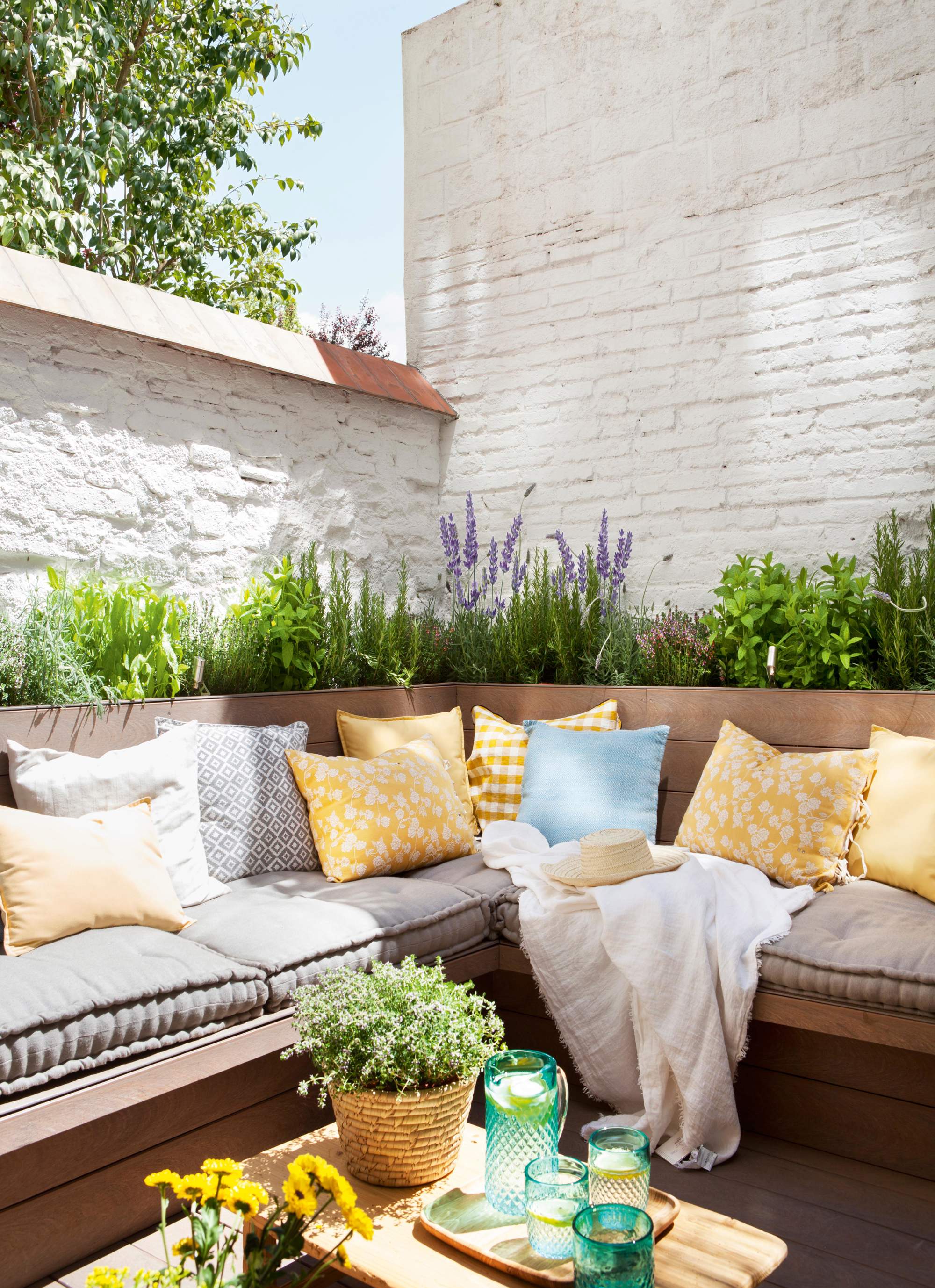 Terraza pequeña con jardineras detrás del sofá de obra