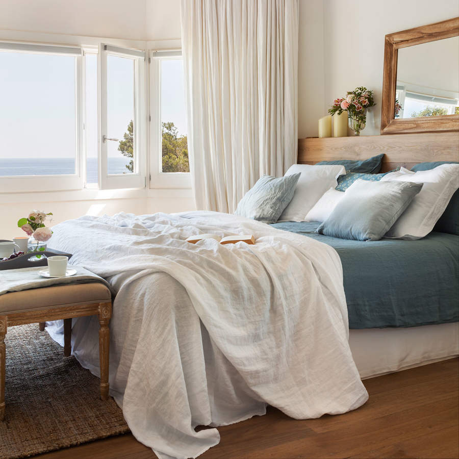 dormitorio con vistas al mar y ropa de cama en blanco y azul 172579e0