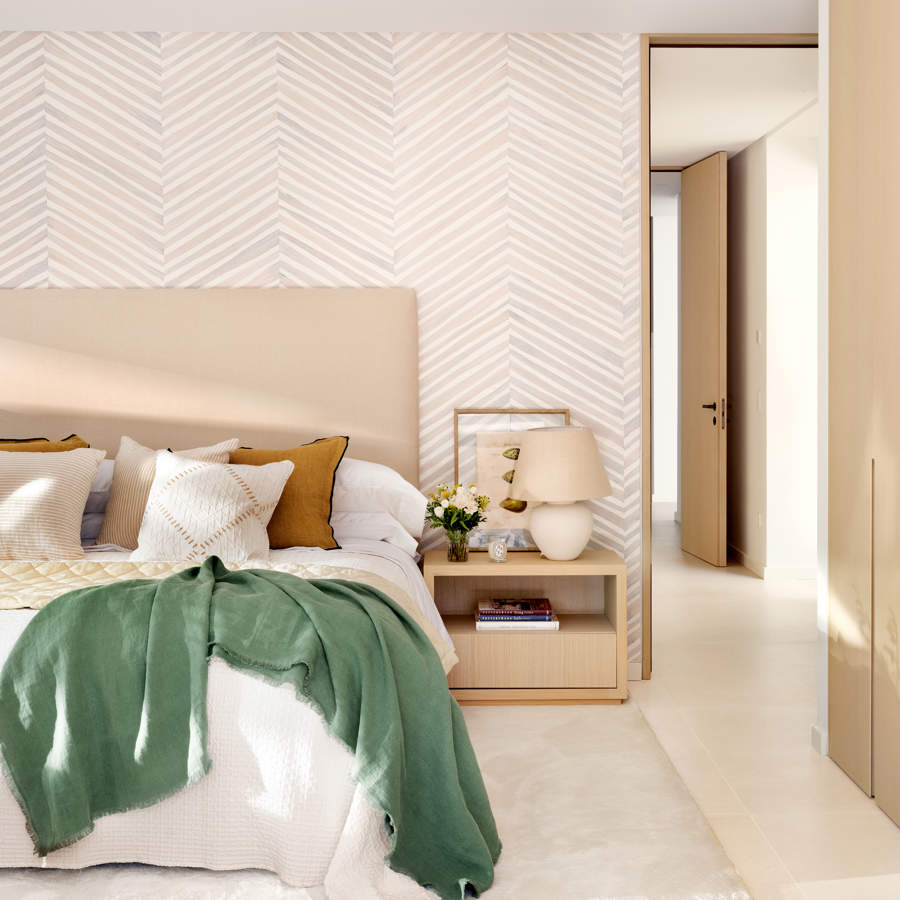 dormitorio con cabecero beige y pared con papel geometrico