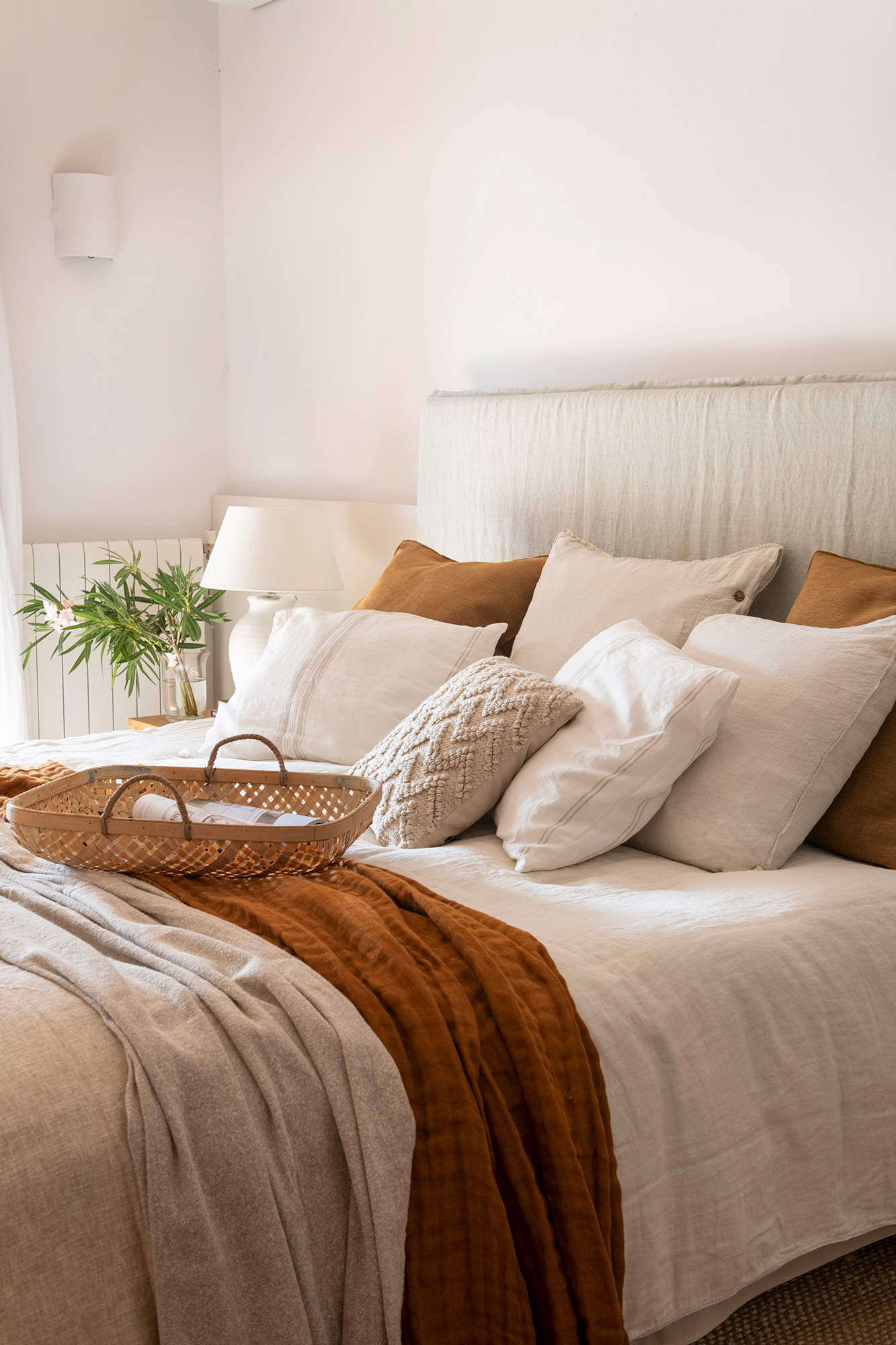 Dormitorio con cama de matrimonio con detalle de cojines crudos y tostados