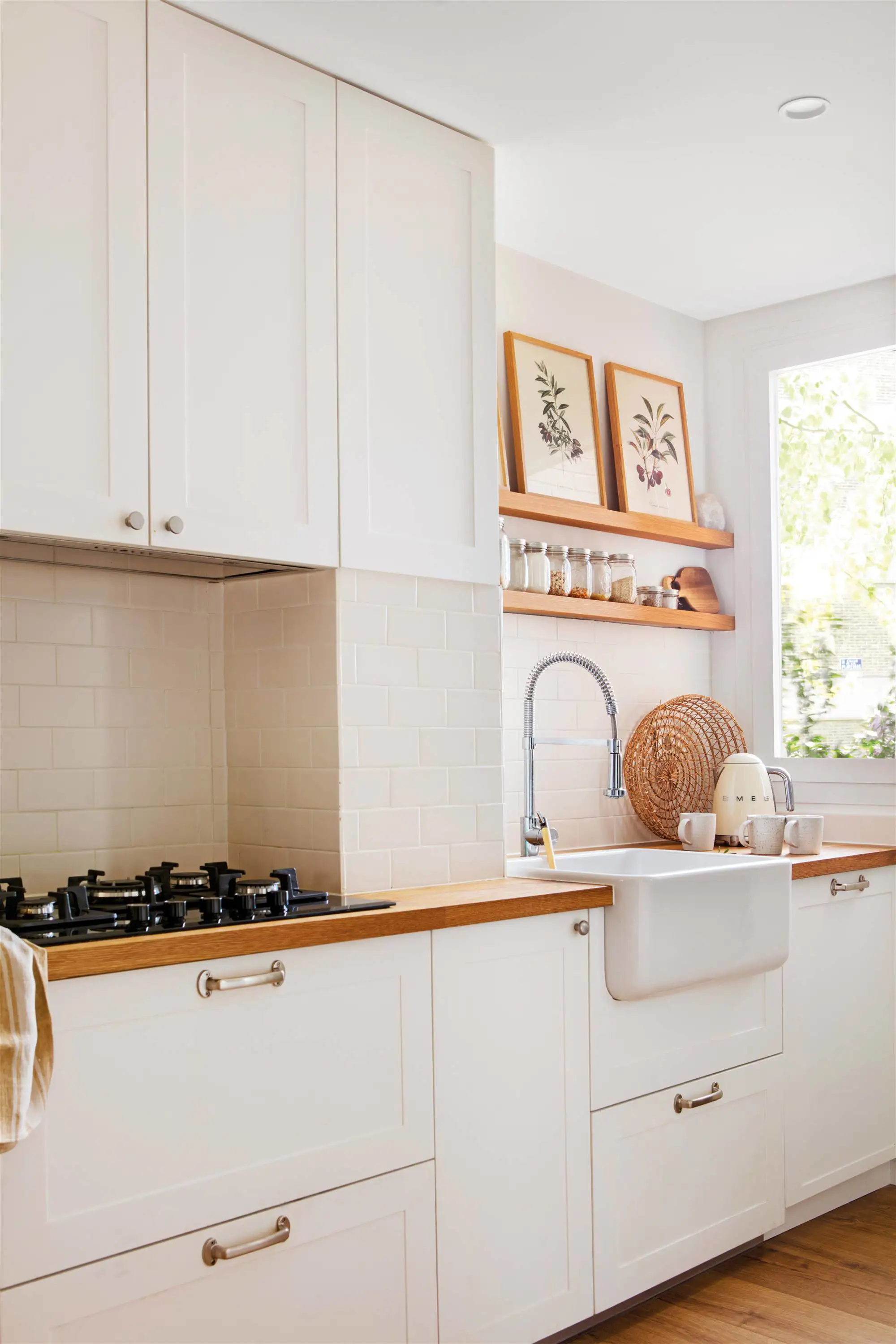 Cocina blanca con encimera y baldas de madera.