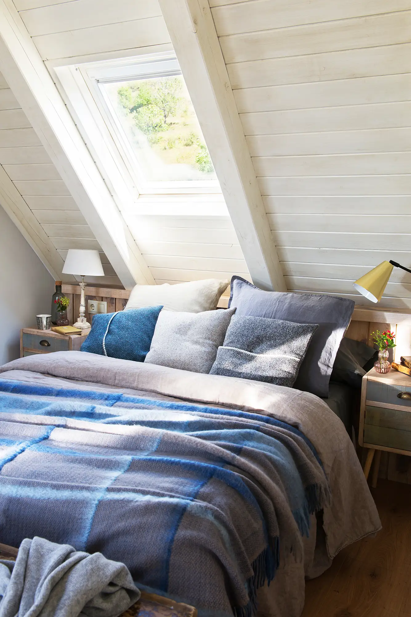 Dormitorio en buhardilla con ropa de cama azul y gris