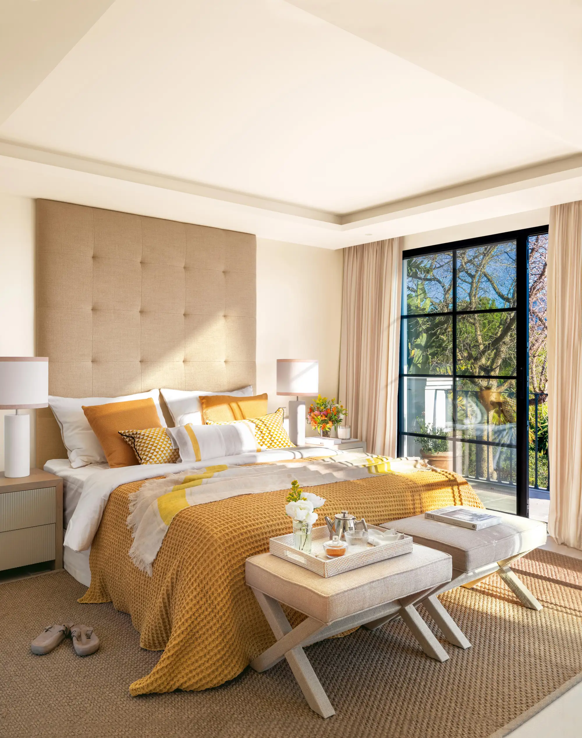 Dormitorio con cabecero alto de capitoné y ropa de cama en color mostaza