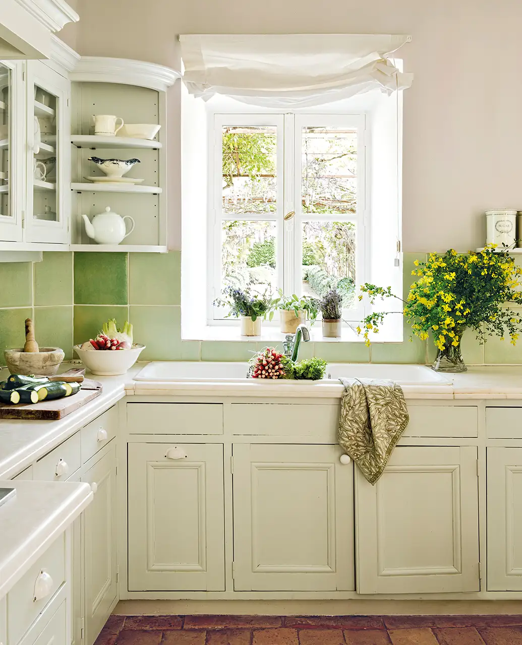 Cocina con azulejos verdes y muebles en blanco