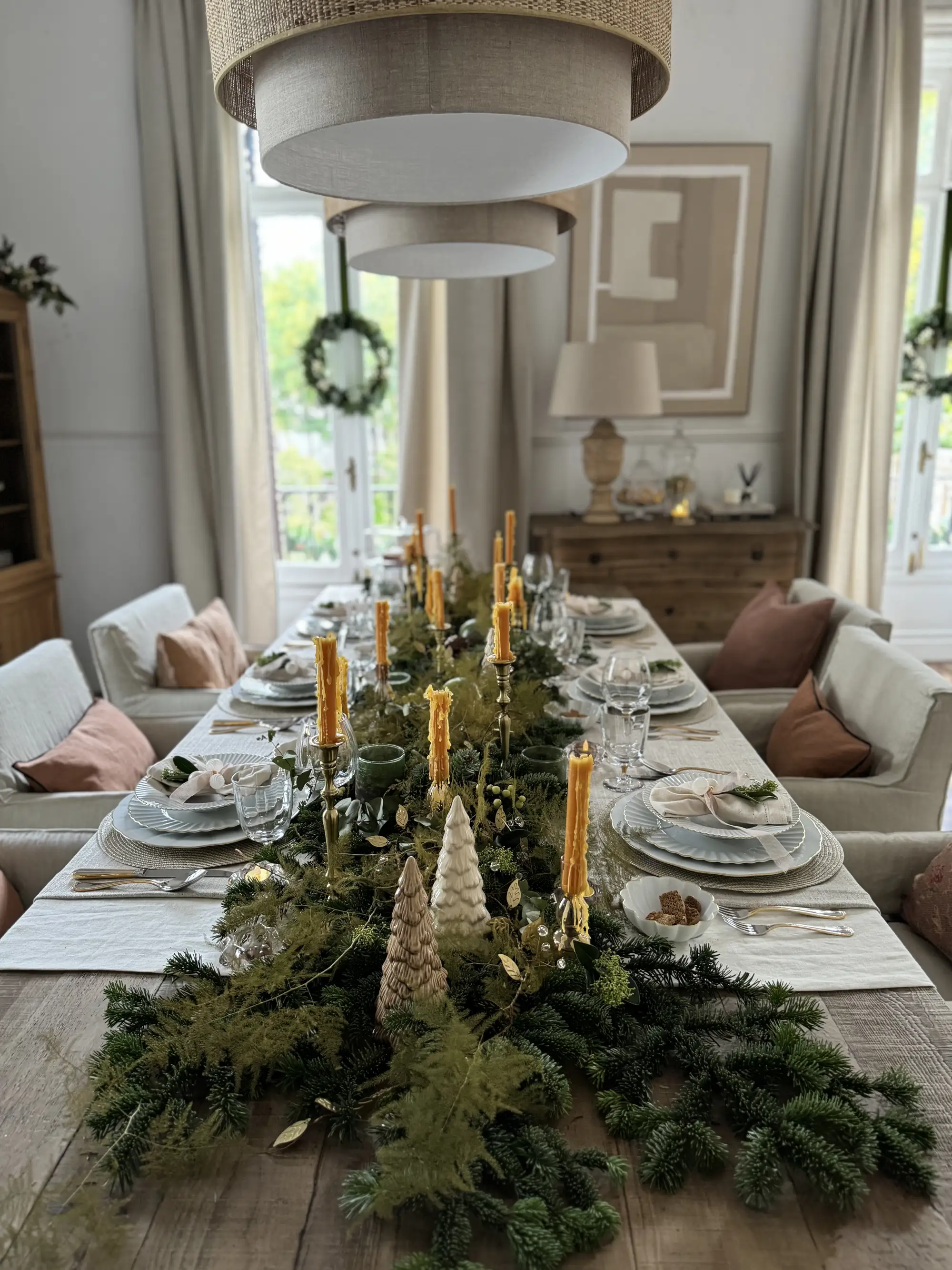 Mesa de comedor decorada con guirnalda natural y detalles de velas aromáticas