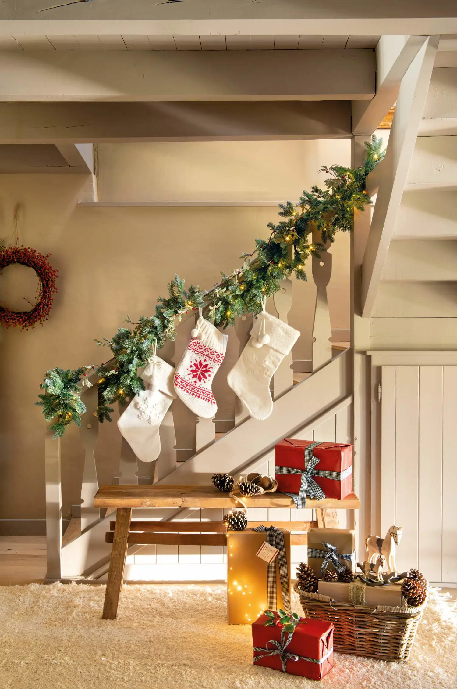 Escalera blanca decorada con guirnaldas, luces cálidas y tres calcetines blancos