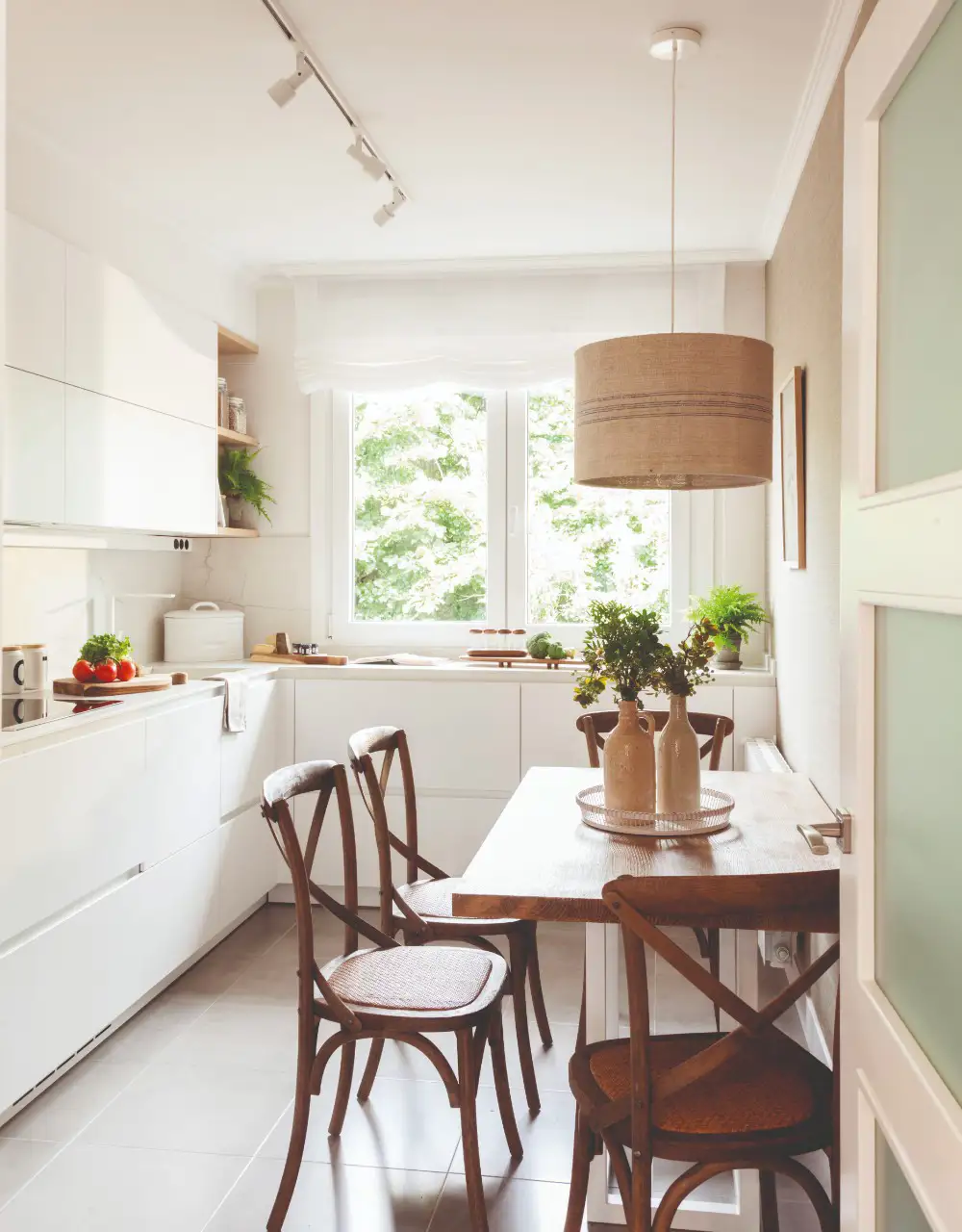 Cocina blanca con comedor con muebles de madera oscura.