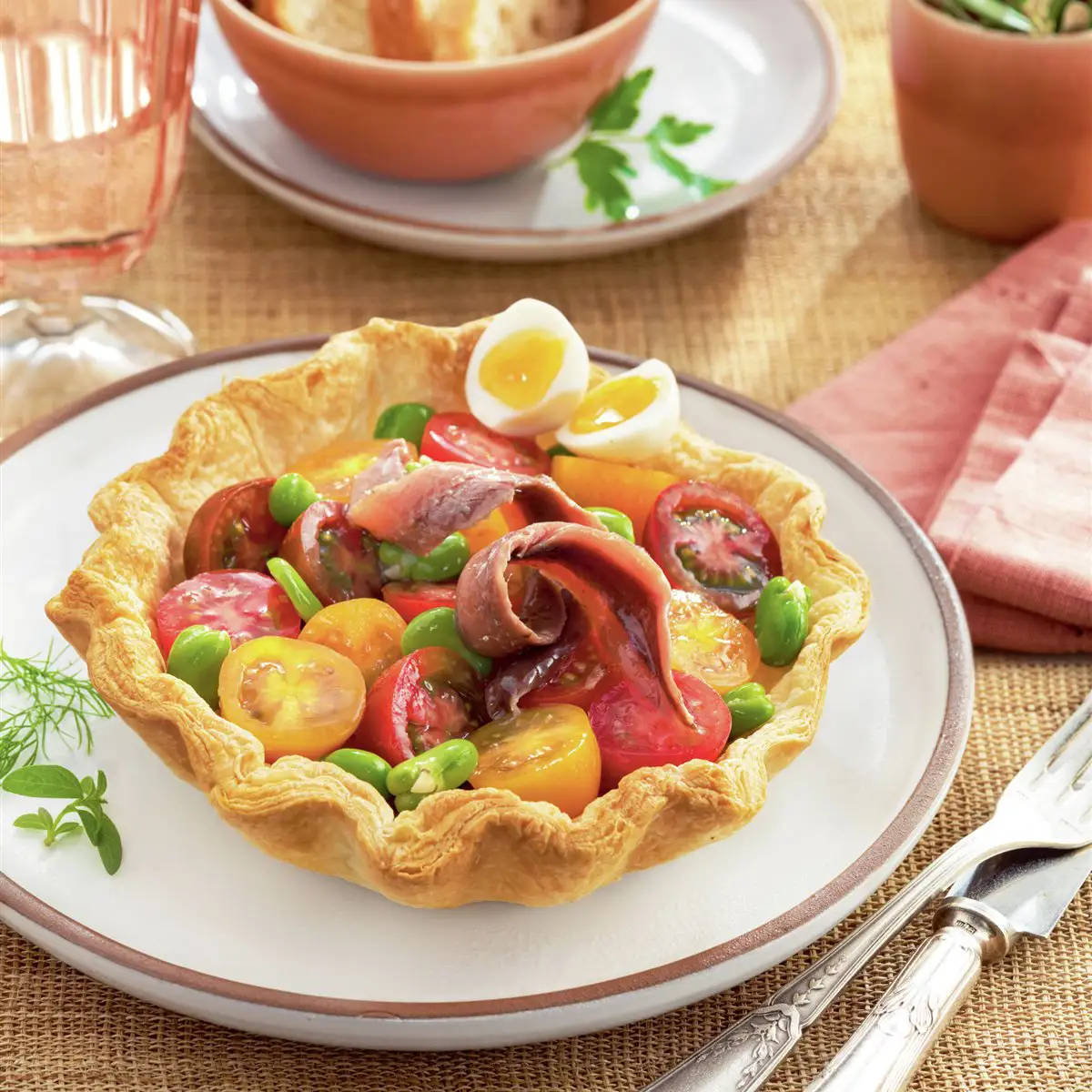 Ensalada de habitas, tomates y anchoas en cesta de hojaldre